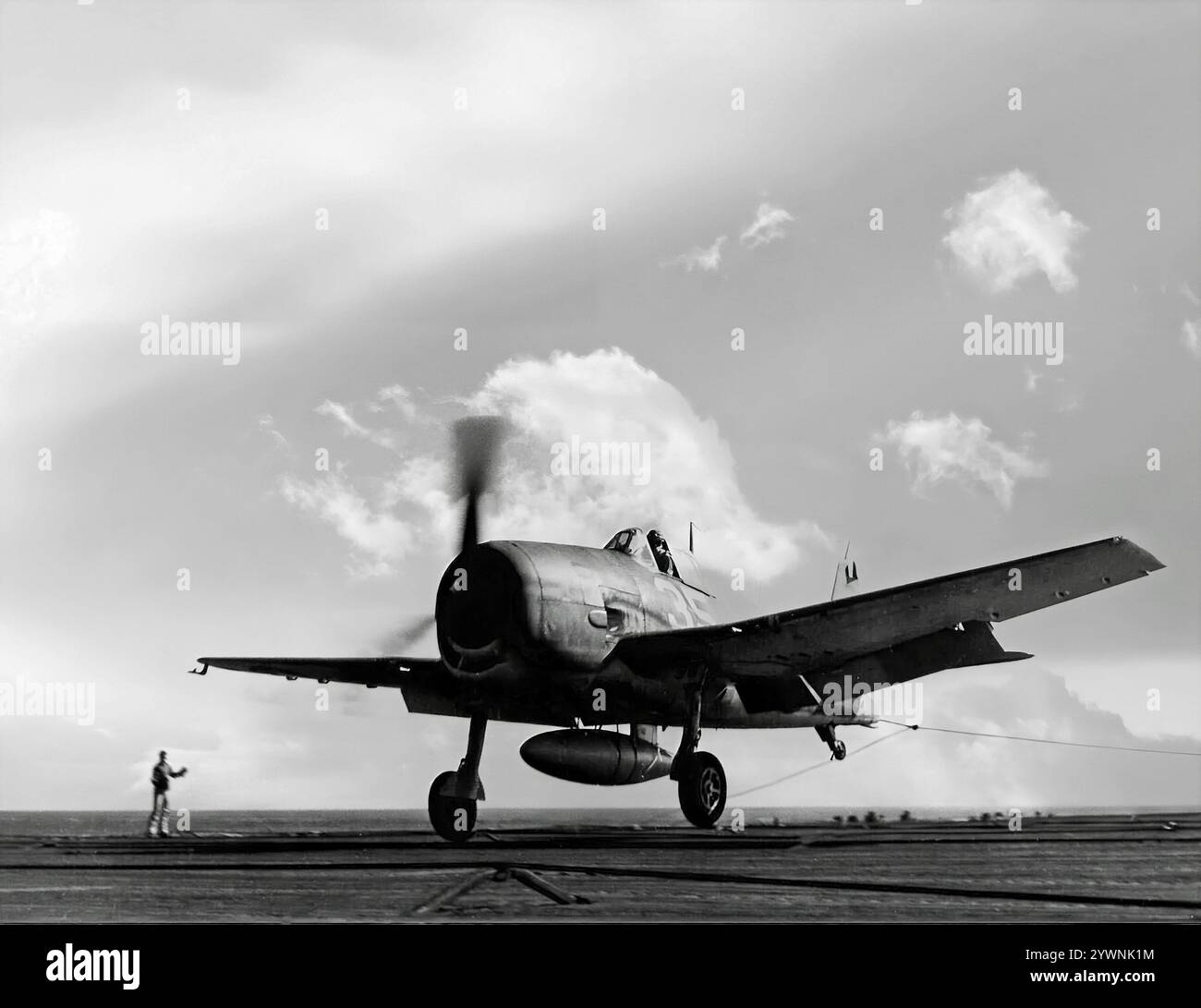 Die Grumman F6F Hellcat, die auf einem Trägerflugdeck landete, war ein US-amerikanisches Trägerflugzeug aus dem Zweiten Weltkrieg, das die frühere F4F Wildcat ersetzen sollte und gegen die japanische Mitsubishi A6M Zero kämpfte. Das Flugzeug hatte sein Kampfdebüt im September 1943 und etablierte sich anschließend als robuster, gut konstruierter Trägerjäger und wurde in der zweiten Hälfte des Pazifikkriegs zum dominierenden Kampfflugzeug der United States Navy. Insgesamt wurden 12.275 in etwas mehr als zwei Jahren gebaut und Hellcats wurde zugeschrieben, während sie im Dienst waren, insgesamt 5.223 feindliche Flugzeuge zu zerstören. Stockfoto