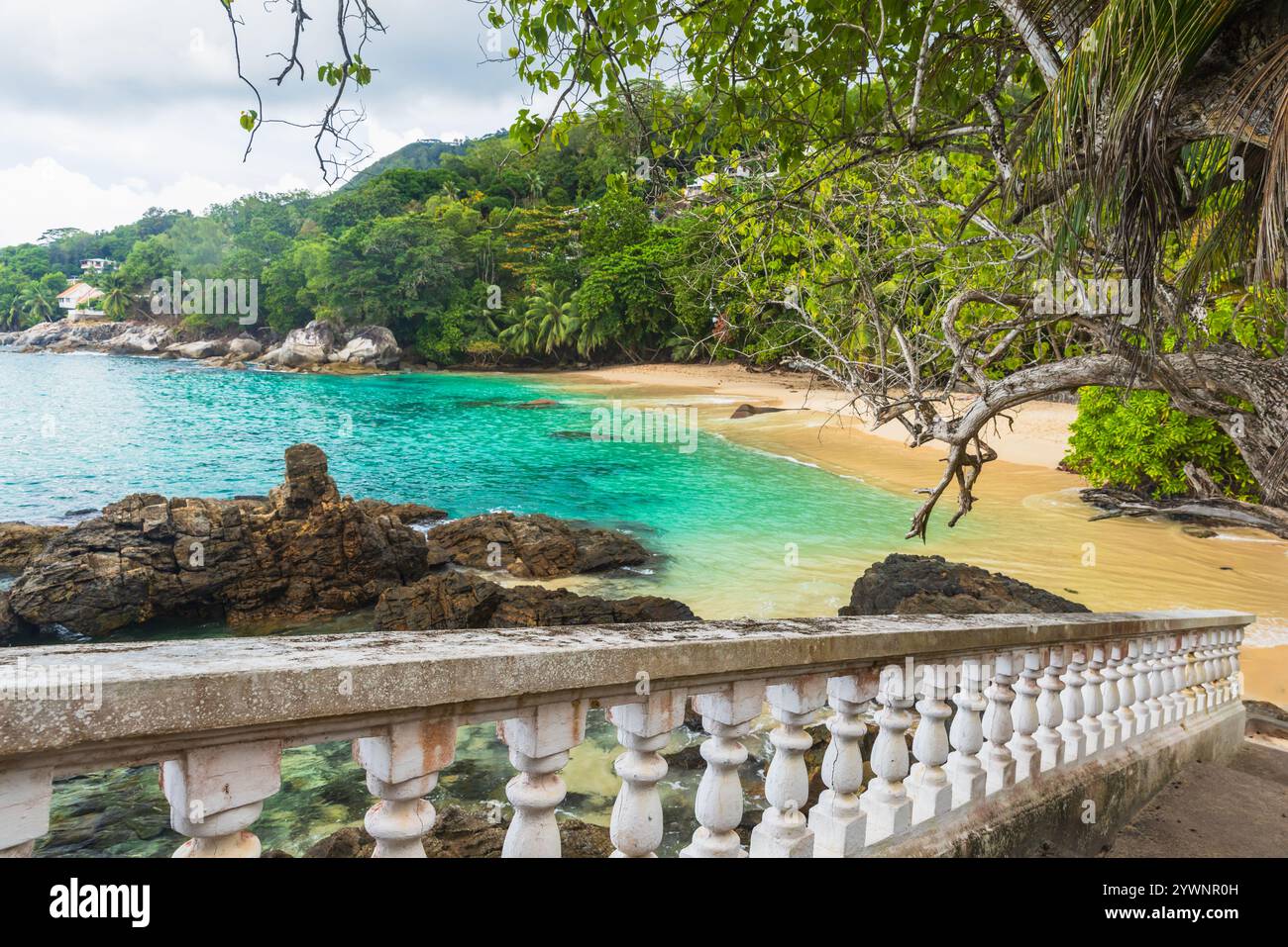 Küstenlandschaft mit einer Treppe und dunklen Felsen an der Küste des Sunset Beach. Mahe Island, Seychellen Stockfoto
