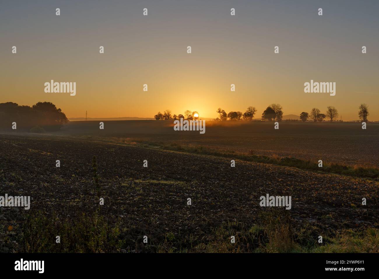 Wunderschöner Sonnenaufgang über den Bergen in der Gegend von noch schattigem Ackerland Stockfoto