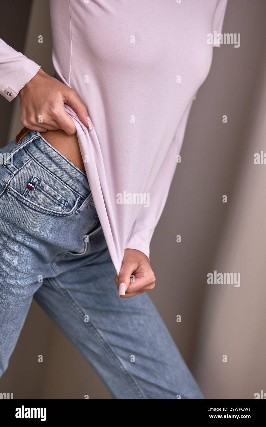 Femininer Freizeitlook mit rosa Oberteil und Jeans Stockfoto