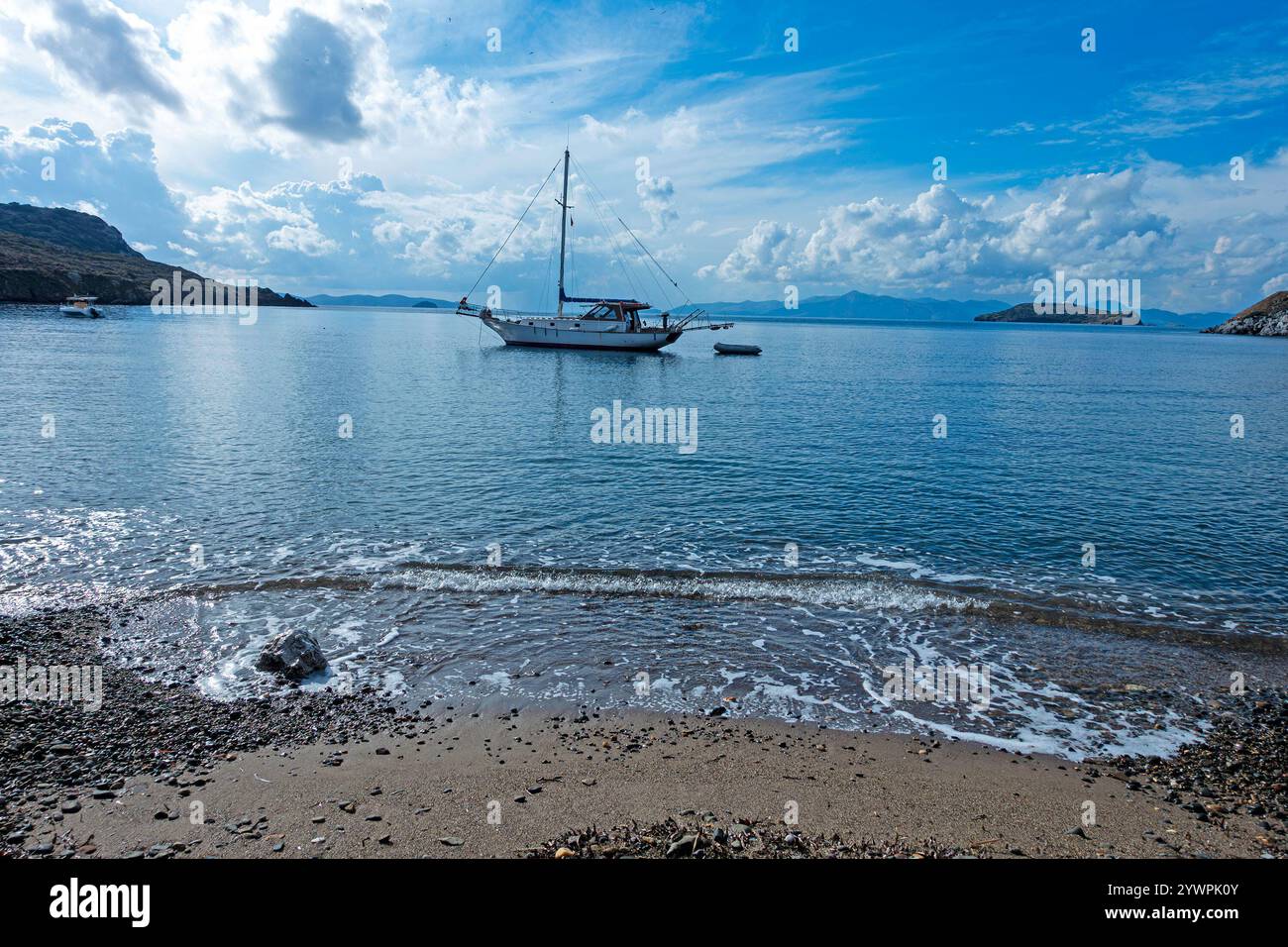 Eine kleine Yacht, die am Strand in Gumusluk vor Anker liegt, in der Nähe von Bodrum, Türkiye Stockfoto