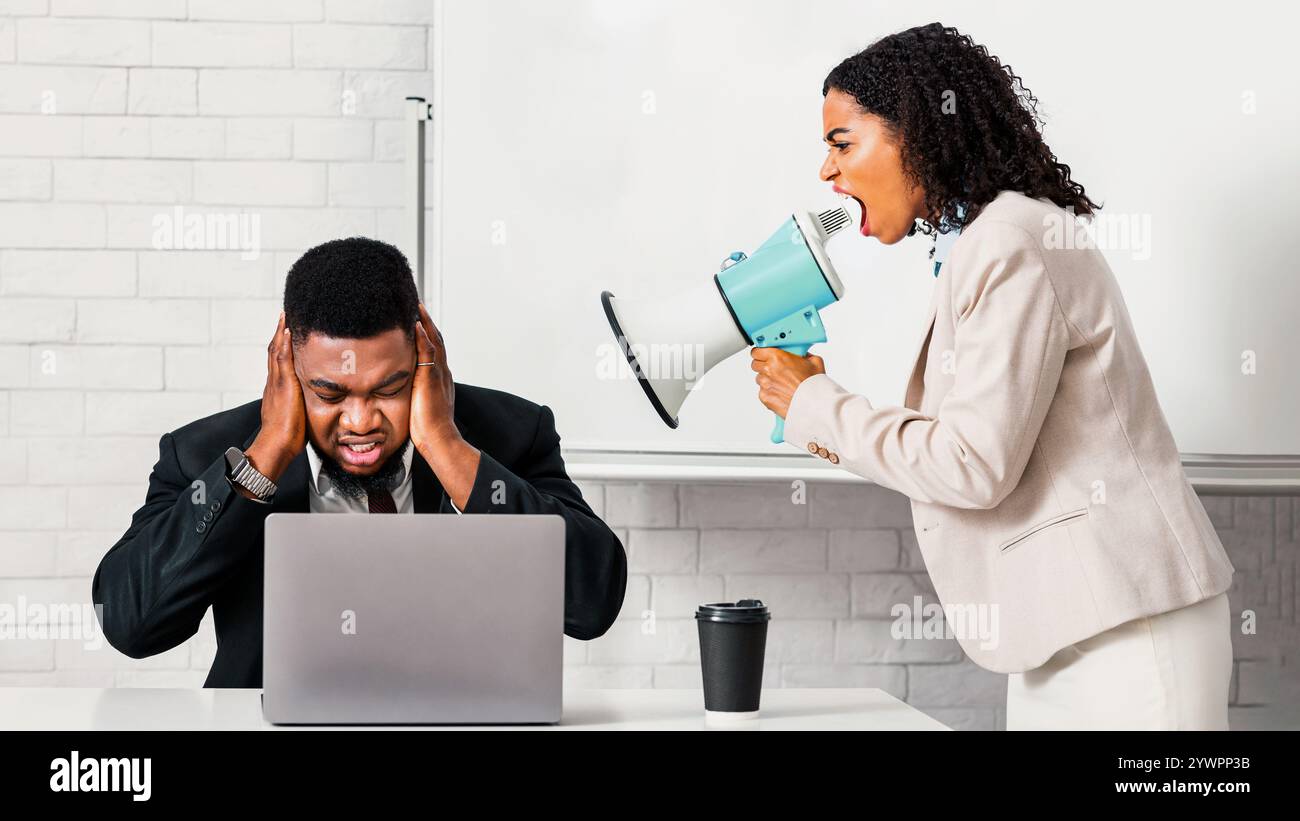 Verärgerte afroamerikanische Dame Boss mit Lautsprecher schreiend verängstigt Männlicher Angestellter im Büro Stockfoto