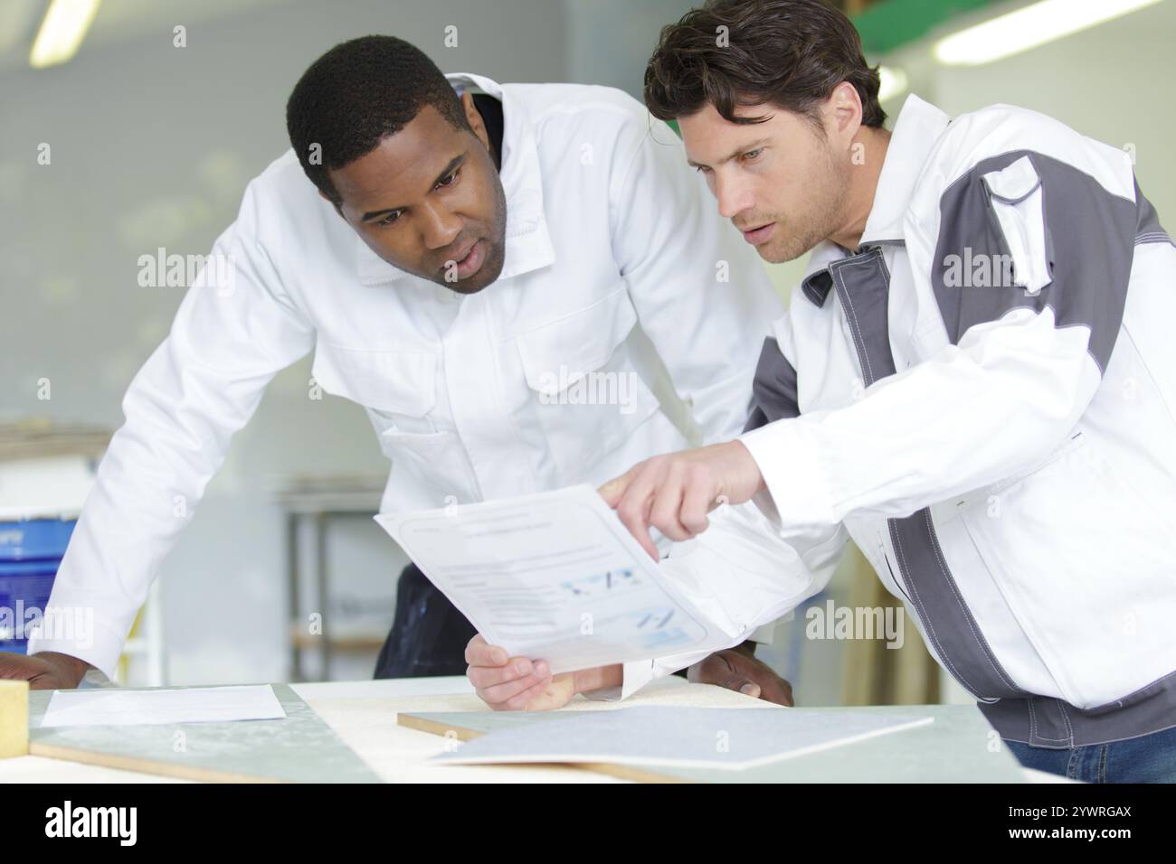 Maler und Lehrling, der sich vor der Arbeit Papiere ansieht Stockfoto