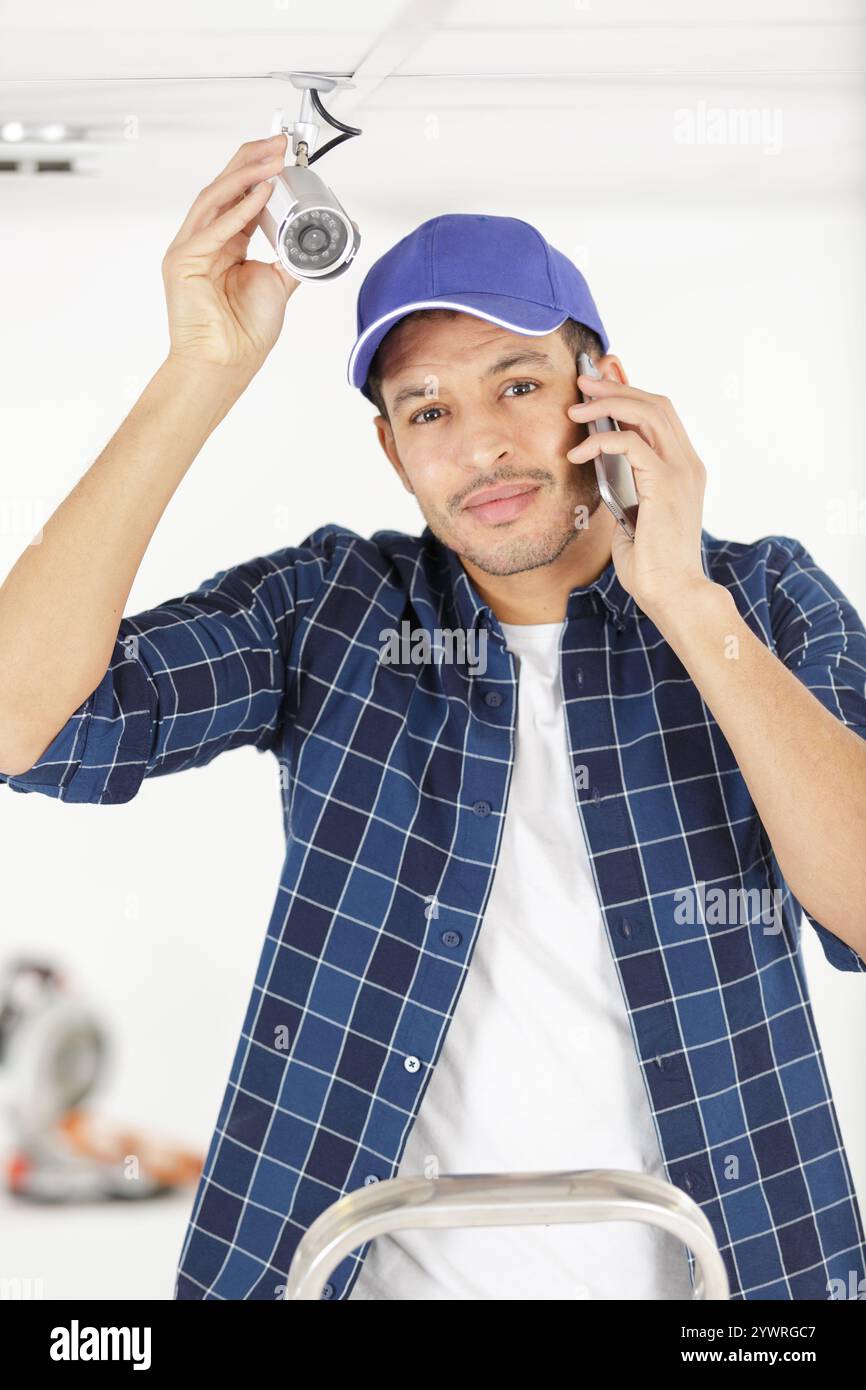 Junger Mann, der eine moderne wi-fi-Überwachungskamera einstellt Stockfoto