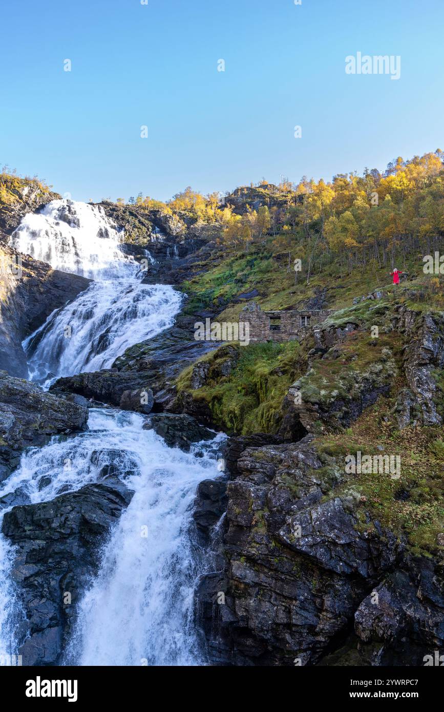 Huldra, der Verführer, tanzt und singt in fließenden roten Kleidern neben dem Kjosfossen-Wasserfall im Flamsdalen-Tal. Huldra ist eine nordische Folklore-Figur Stockfoto