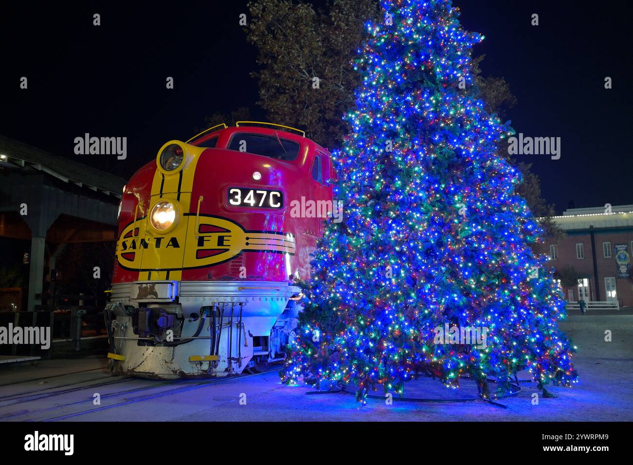 Eine rote Lokomotive und ein beleuchteter Weihnachtsbaum am historischen Bahnhof Old Sacramento CA Stockfoto