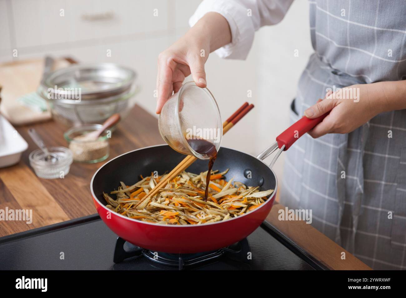 Eine Frau würzt den Kinpira Gobo Stockfoto