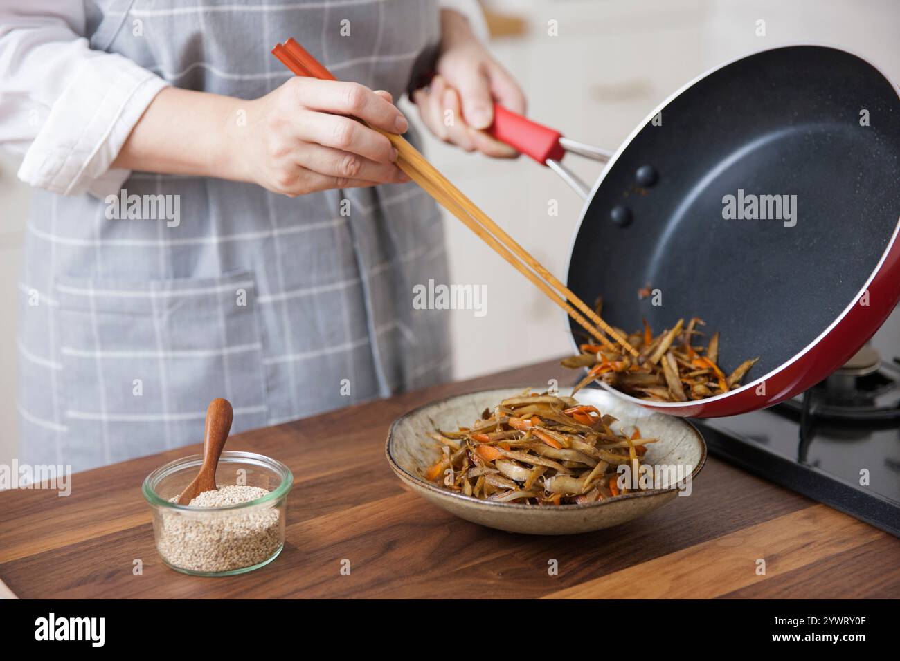 Frau, die Kinpira Gobo in einer Schüssel mit Essstäbchen arrangiert Stockfoto