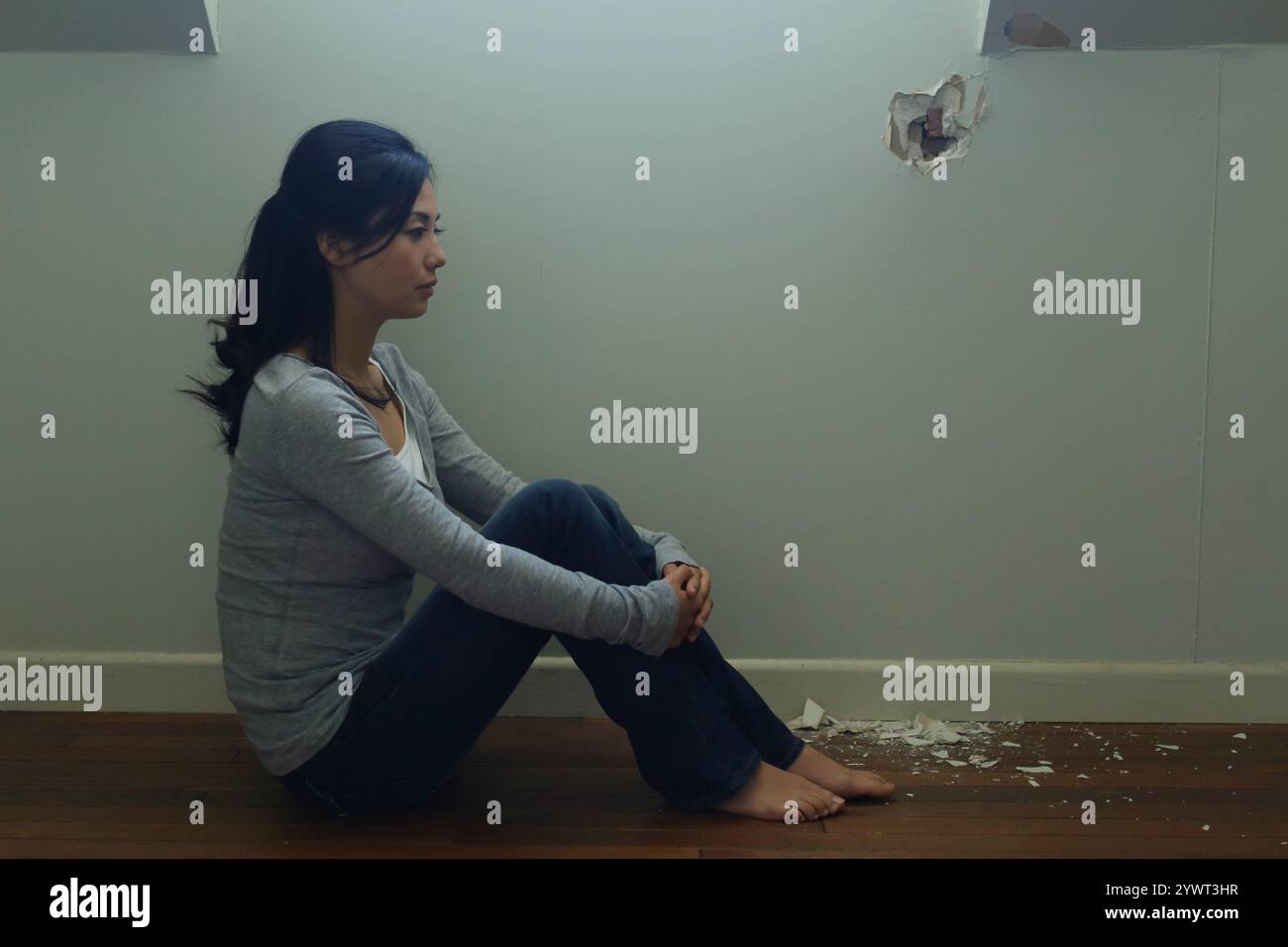 Einsame Frau, die in einem schwach beleuchteten Raum sitzt Stockfoto