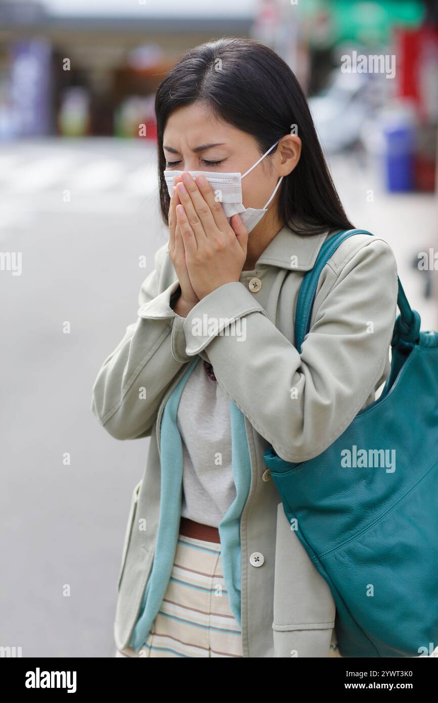 Frau mit Erkältungssymptomen, die eine Maske trägt Stockfoto