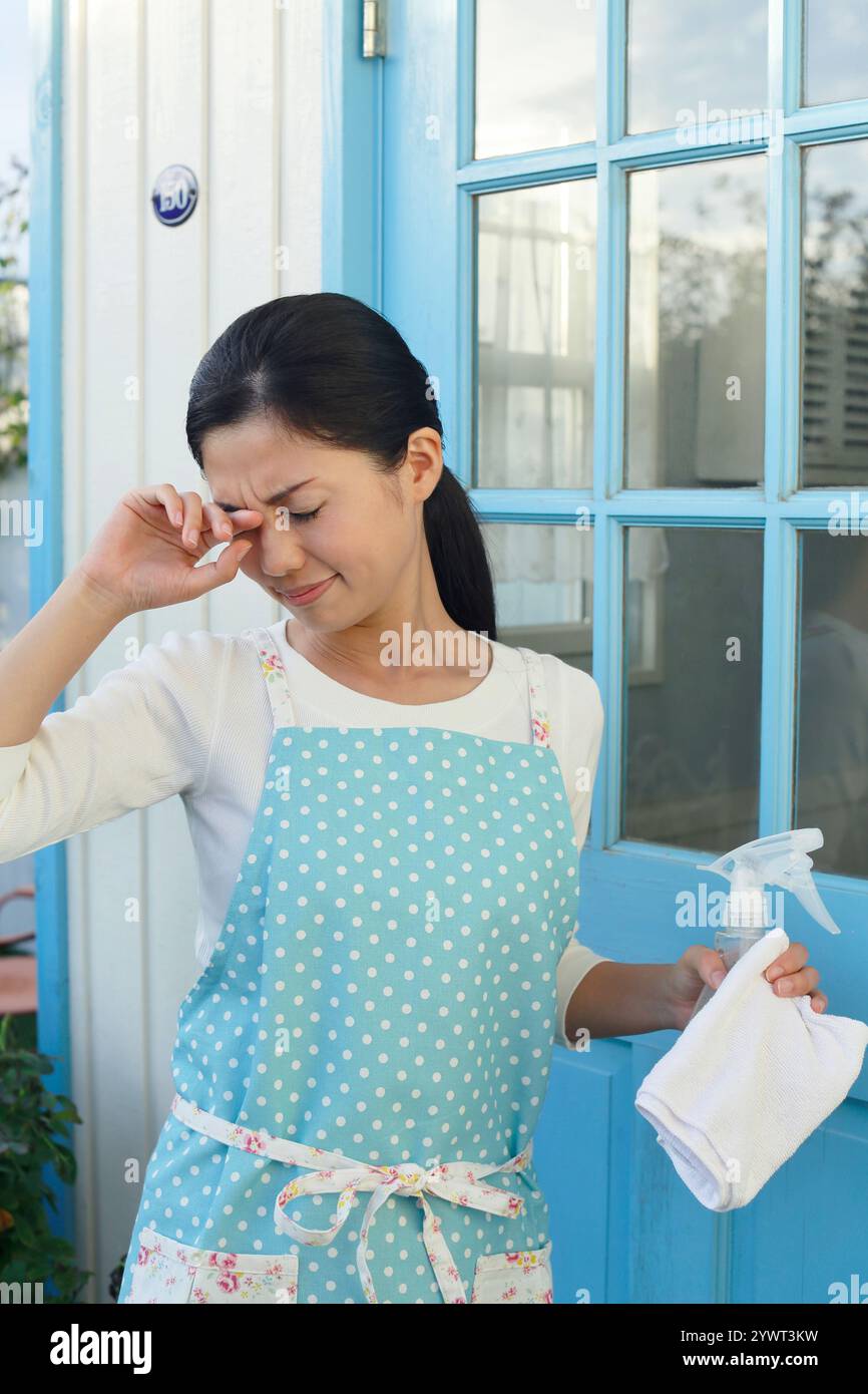 Hausfrau reibt sich die Augen während der Hausarbeit Stockfoto