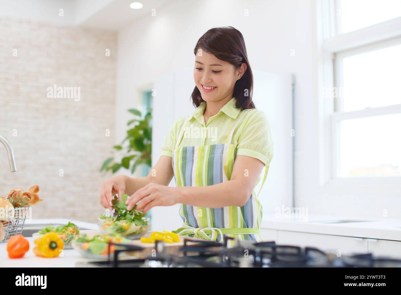 Frau, die in einer gut beleuchteten Küche kocht Stockfoto