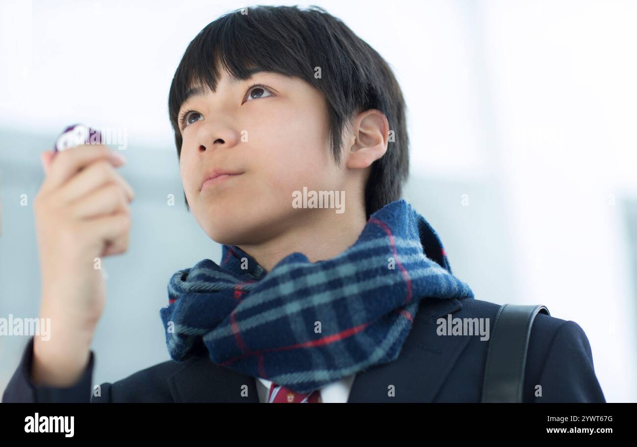 Männlicher Student, der mit Amulett aufblickt Stockfoto