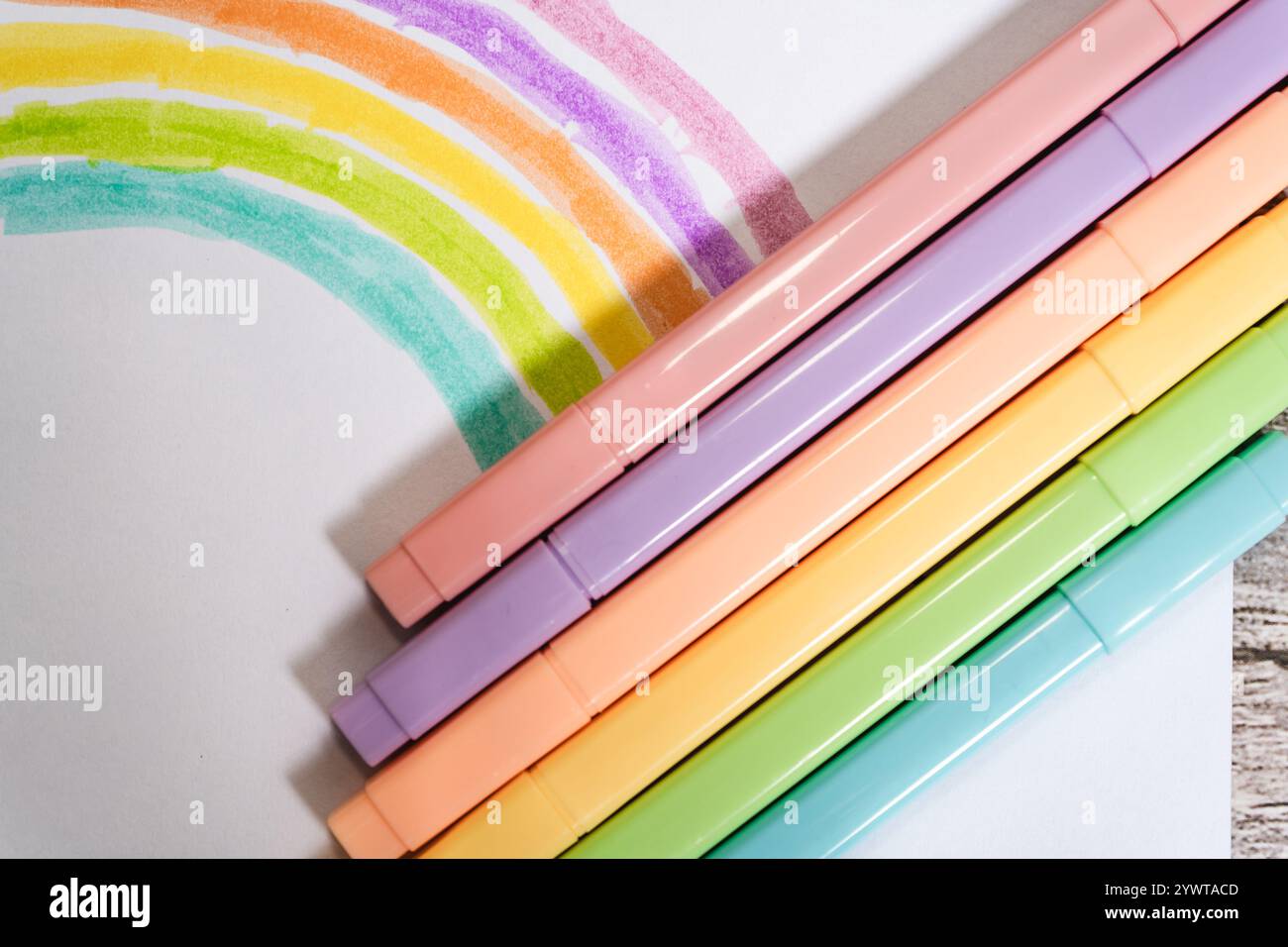 Pastellmarker und Zeichnung eines Regenbogens auf einem weißen Blatt Stockfoto