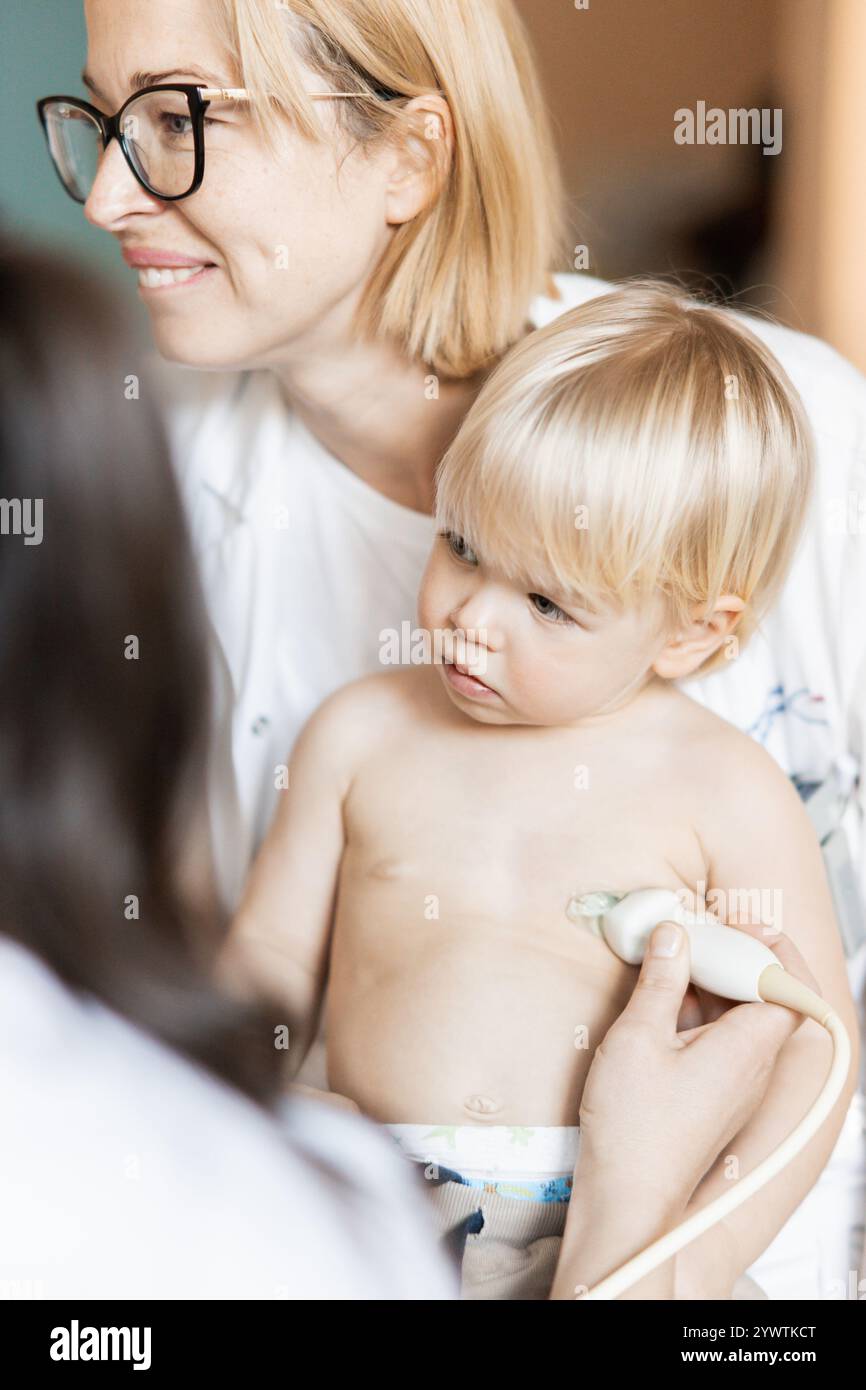 Kleinkind, das im Rahmen der regelmäßigen ärztlichen Untersuchung beim Kinderarzt durch Herzsonographie durch Kardiologen auf Herzgeräusche untersucht wird Stockfoto