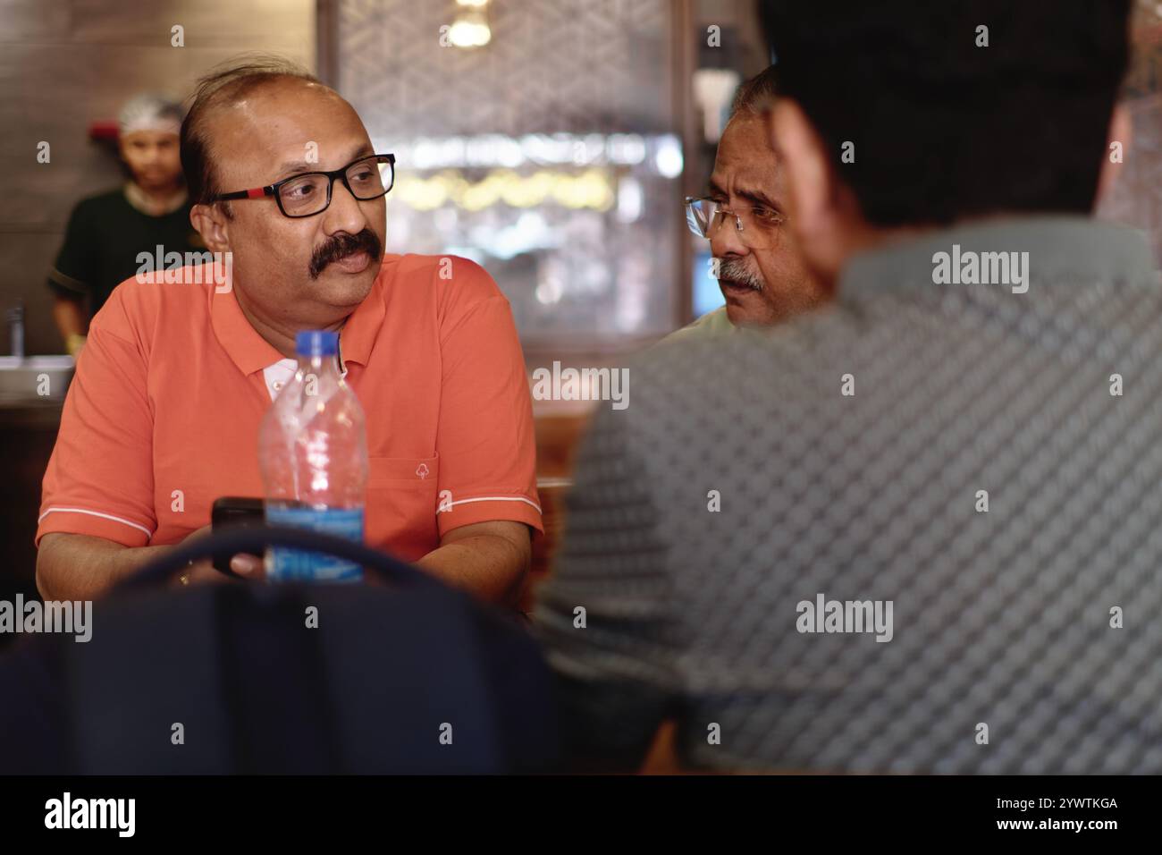 Drei indische Männer mittleren Alters unterhalten sich bei einer Mahlzeit in einem Restaurant in Dadar, Mumbai, Indien Stockfoto