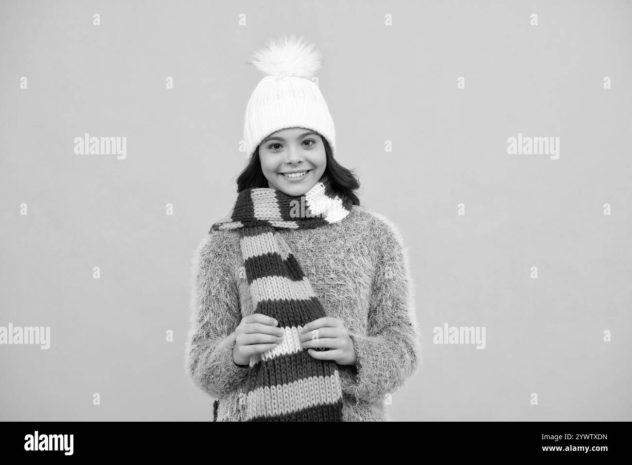 Moderne Teenager-Mädchen trägt Pullover und Strickmütze auf isolierten gelben Hintergrund. Glückliches Mädchengesicht, positive und lächelnde Emotionen. Stockfoto