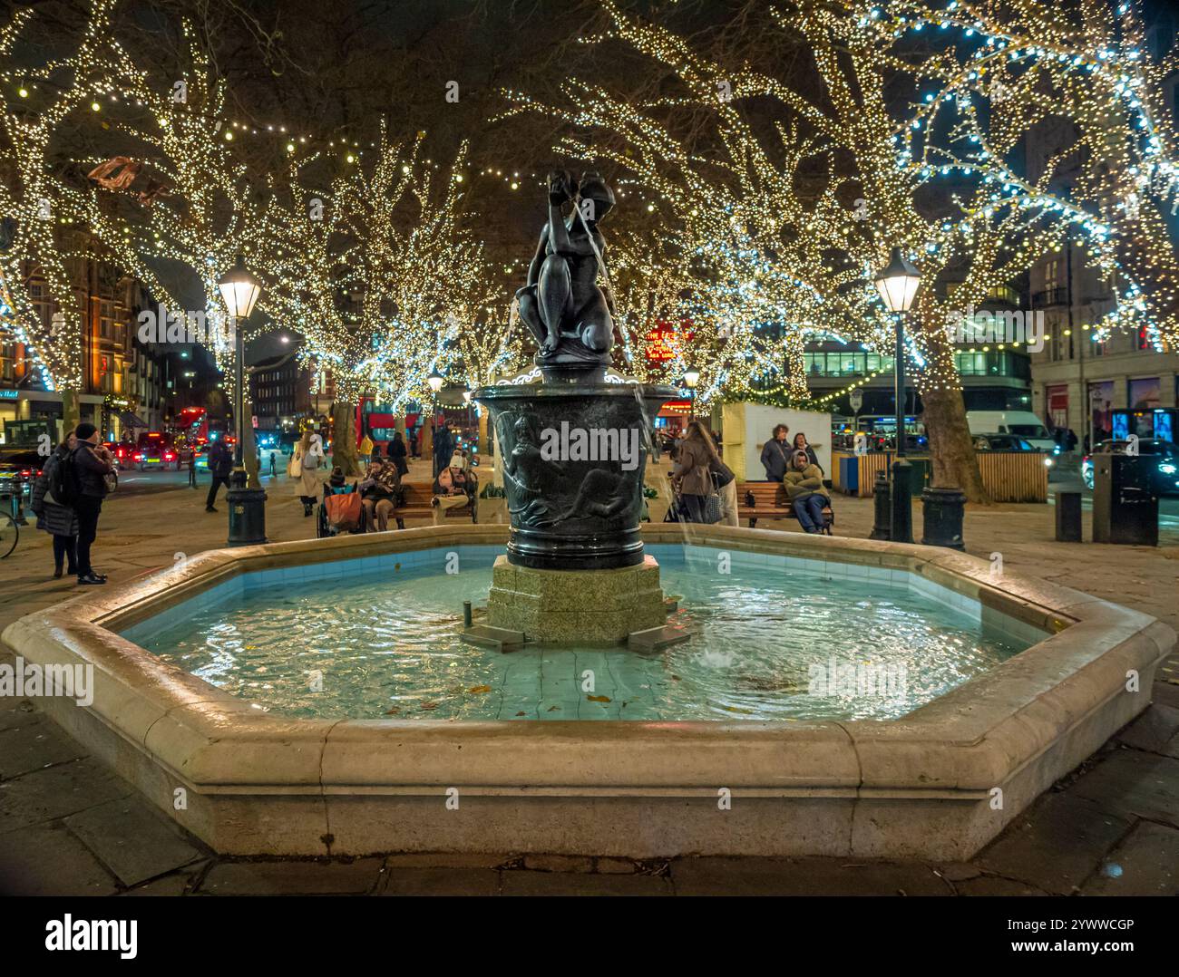 Helle Weihnachtslichter umgeben den Venus-Brunnen am Sloane-Platz und verzaubern Besucher mit einem festlichen Leuchten, während sie den Winterabend genießen. Stockfoto