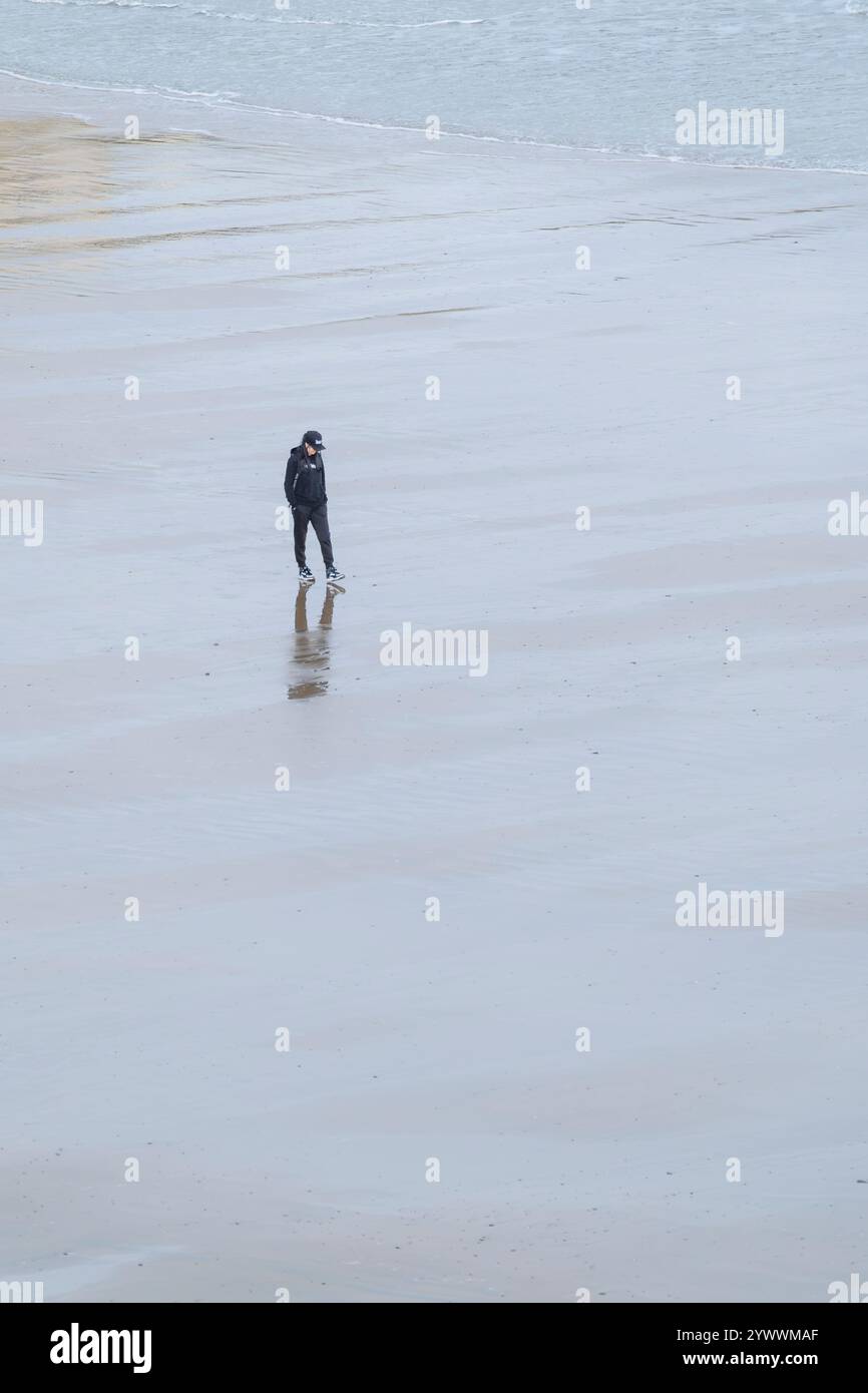 Eine Person, die bei Ebbe in Newquay Cornwall, Großbritannien, über den Towan Beach läuft. Stockfoto