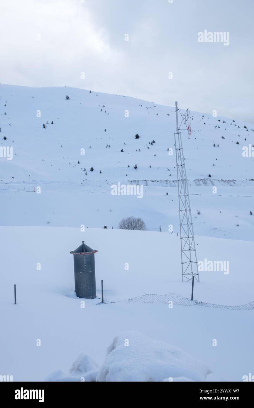 Vall de Boi zeigt eine schneebedeckte Fläche, wo sich neben einem kleinen Gebäude ein Kommunikationsturm erhebt. Die ruhige Winterlandschaft lädt zur Ruhe und Entspannung ein Stockfoto