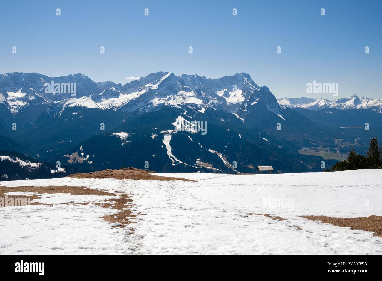 Schnee bedeckt die atemberaubenden Berge von Garmisch-Partenkirchen, Bayern, und zeigt die Schönheit des Winters. Der klare blaue Himmel ergänzt das imposante Stockfoto