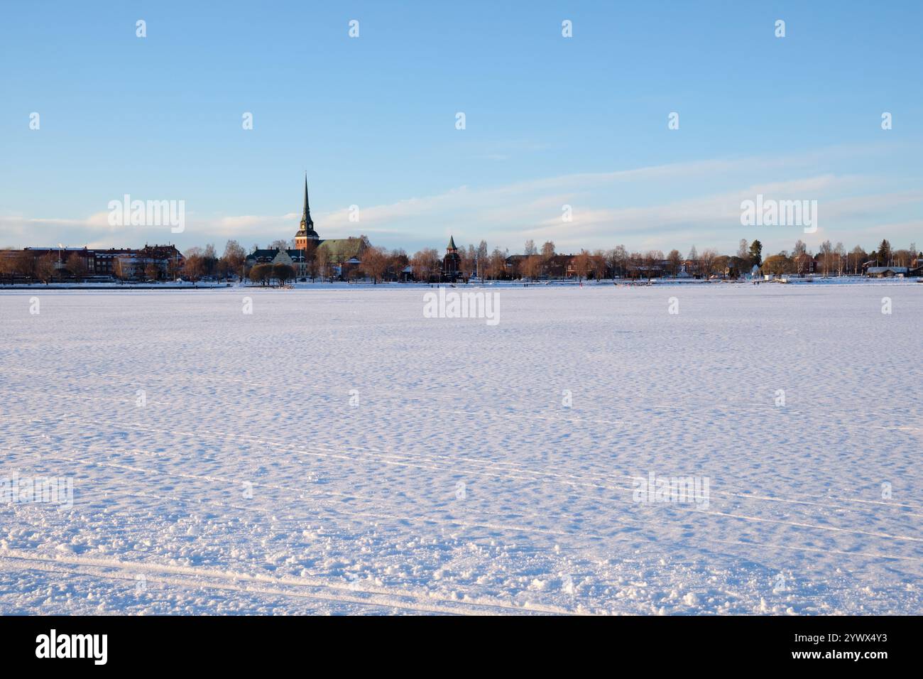 Eine ruhige Winterlandschaft in Mora, Dalarna, Schweden. Die Szene zeigt eine riesige schneebedeckte Weite mit einem Kirchturm, der in der Ferne zu sehen ist Stockfoto