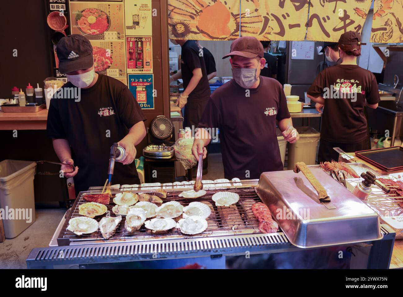 Männer bereiten Meeresfrüchte in einem Restaurant am Straßenrand in der Outer Tsukiji Market Area, Tsukiji, Chuo City, Tokio, Japan, Asien zu. Stockfoto