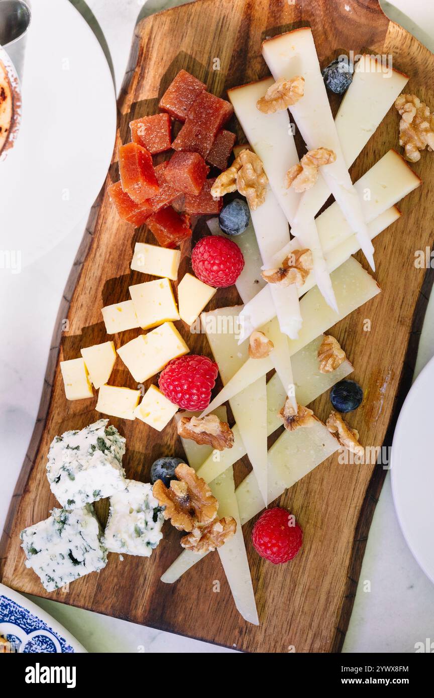 Ein wunderschönes Bild von einer Holzkäseplatte mit einer Auswahl an Käsesorten, Stockfoto