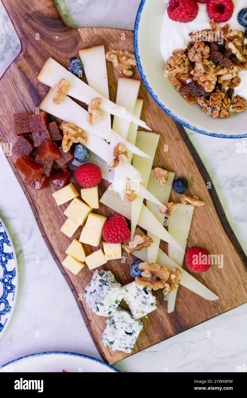 Ein wunderschönes Bild von einer Holzkäseplatte mit einer Auswahl an Käsesorten, Stockfoto