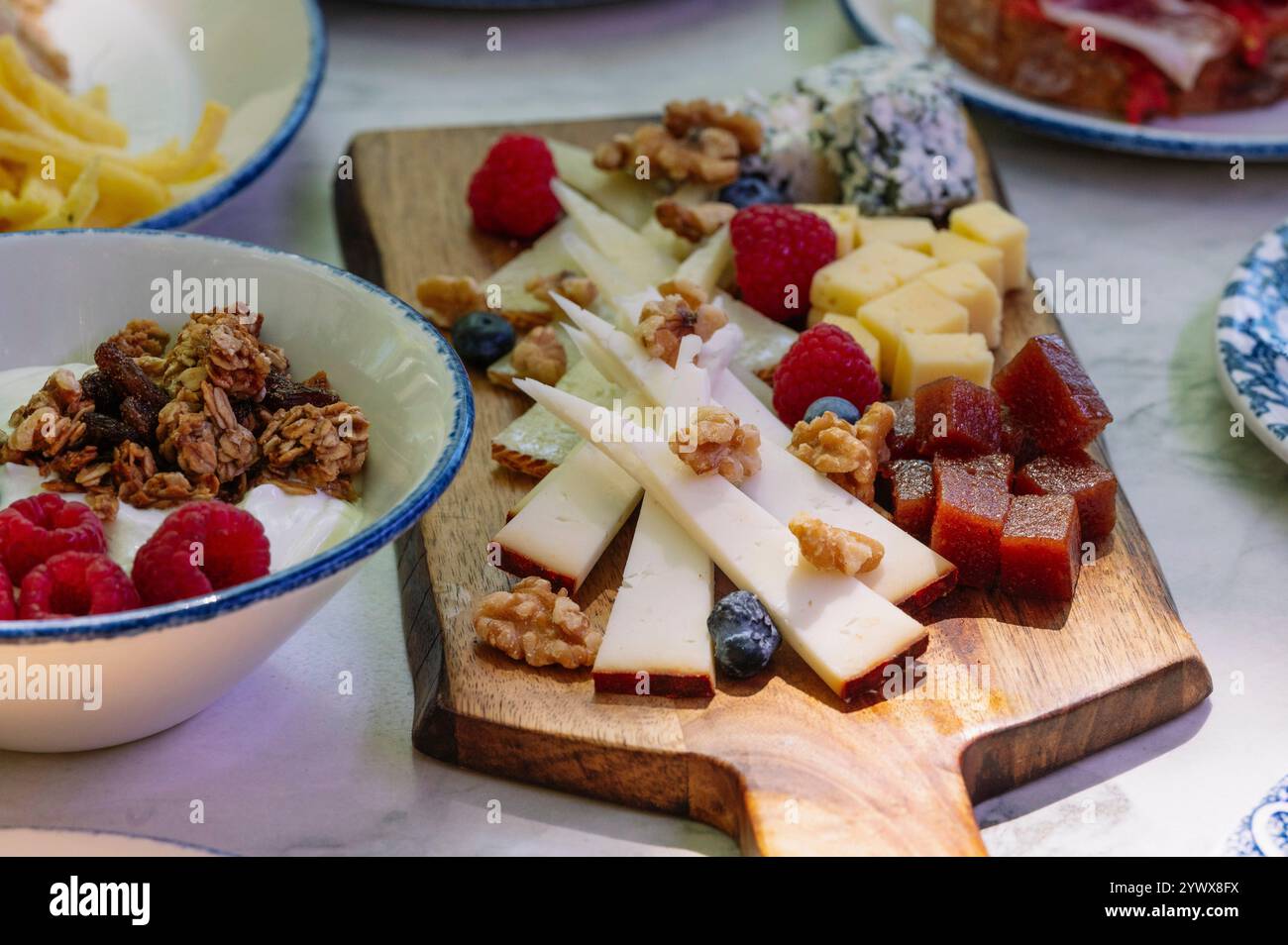 Ein wunderschönes Bild von einer Holzkäseplatte mit einer Auswahl an Käsesorten, Stockfoto