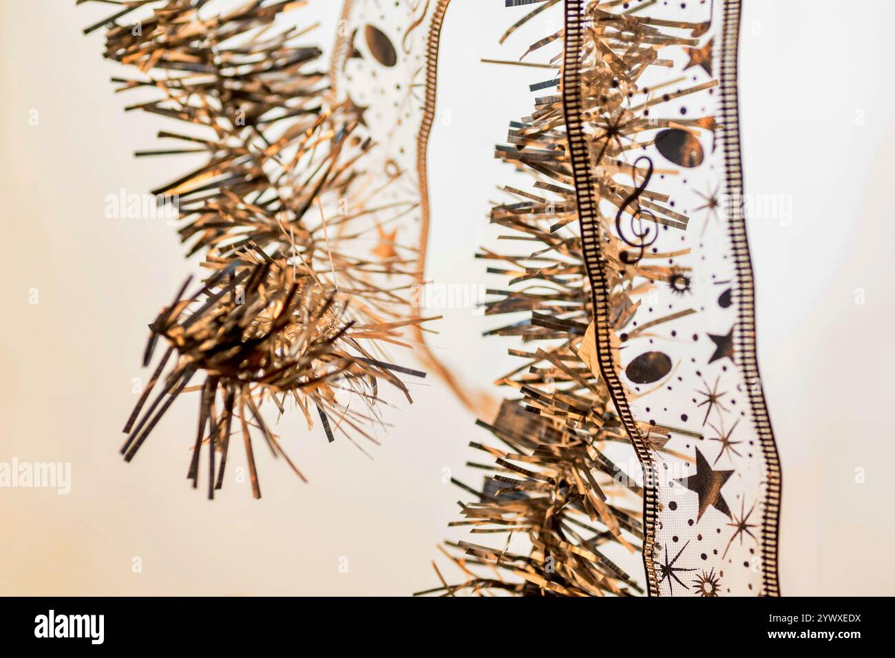 Zwei dekorative Schleife mit kleinem Stern, Punkt und Violinschlüssel und zwei glänzende goldene Kette, die in hellem Hintergrund hängt, Großaufnahme. Weihnachtsmotiv. Stockfoto