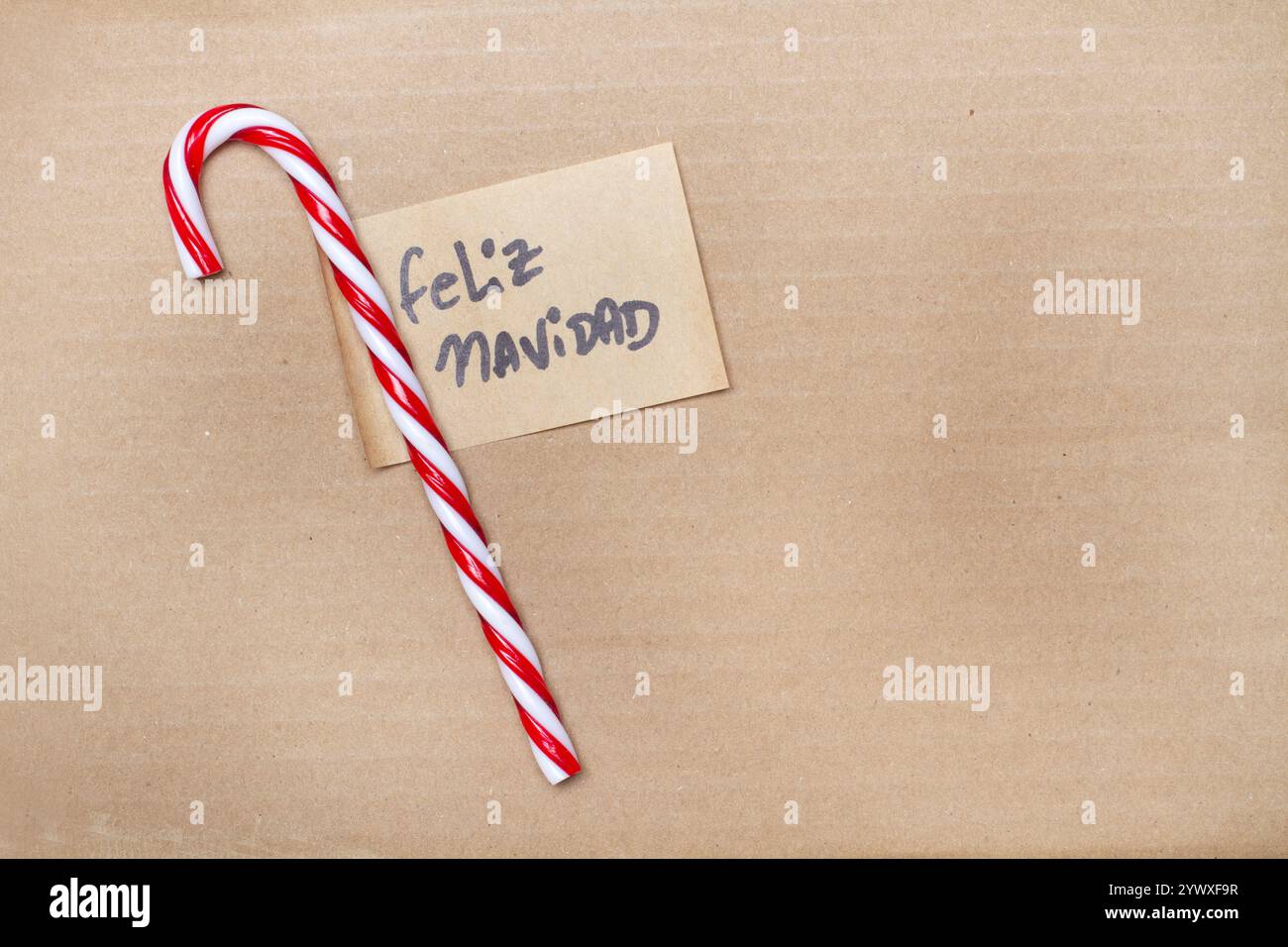 Rot-weiß gestreifter Zuckerrohr mit einer feliz navidad-Nachricht auf braunem Hintergrund mit Kopierraum (trad. merry christmas) Stockfoto
