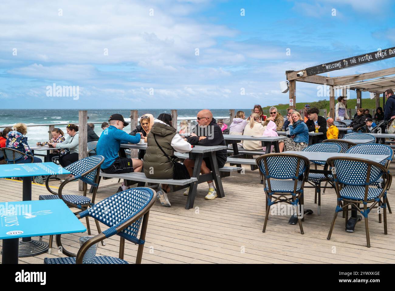 Urlauber sitzen an Picknicktischen auf dem Terrassenbereich der Fistral Beach Bar in Newquay in Cornwall, Großbritannien. Stockfoto