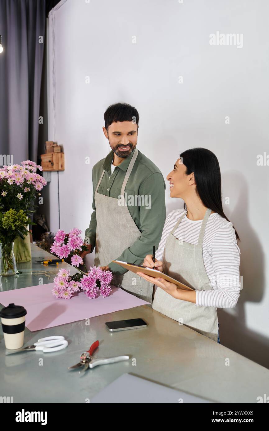 Verheiratetes Paar bereitet fröhlich schöne Blumenarrangements zusammen in ihrem Geschäft vor. Stockfoto