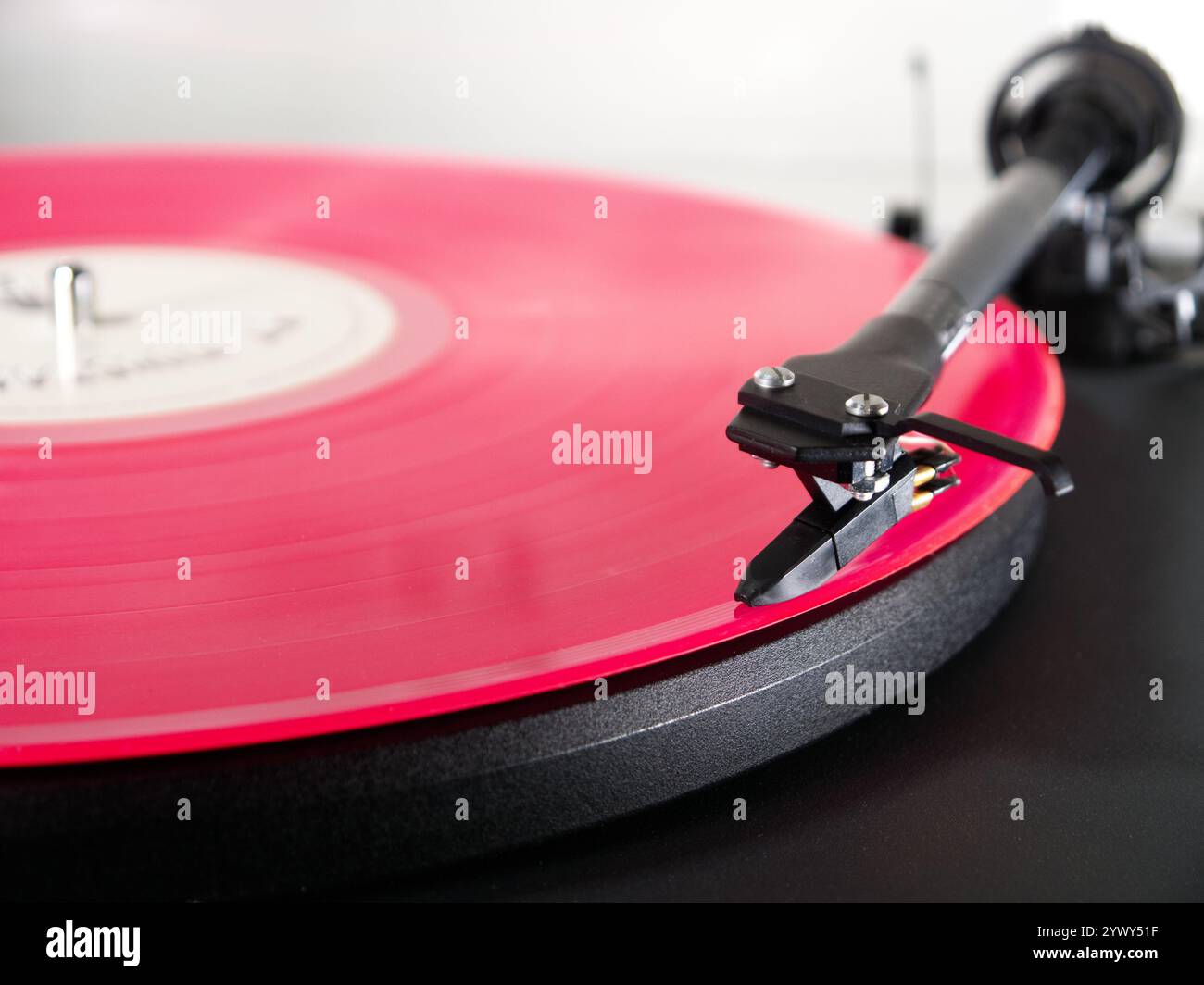 Nahaufnahme einer rosafarbenen LP auf einem Plattenspieler, wobei der Tonarm/die Nadel/der Stift am Anfang des ersten Musiktitels positioniert und abspielbereit ist. Stockfoto