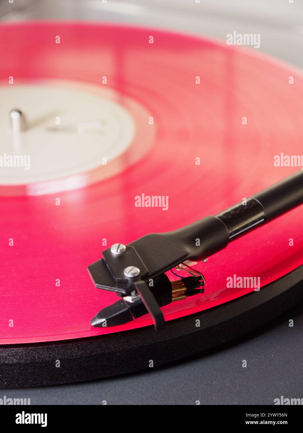 Nahaufnahme einer rosafarbenen LP auf einem Plattenspieler, wobei der Tonarm/die Nadel/der Stift am Anfang des ersten Musiktitels positioniert und abspielbereit ist. Stockfoto