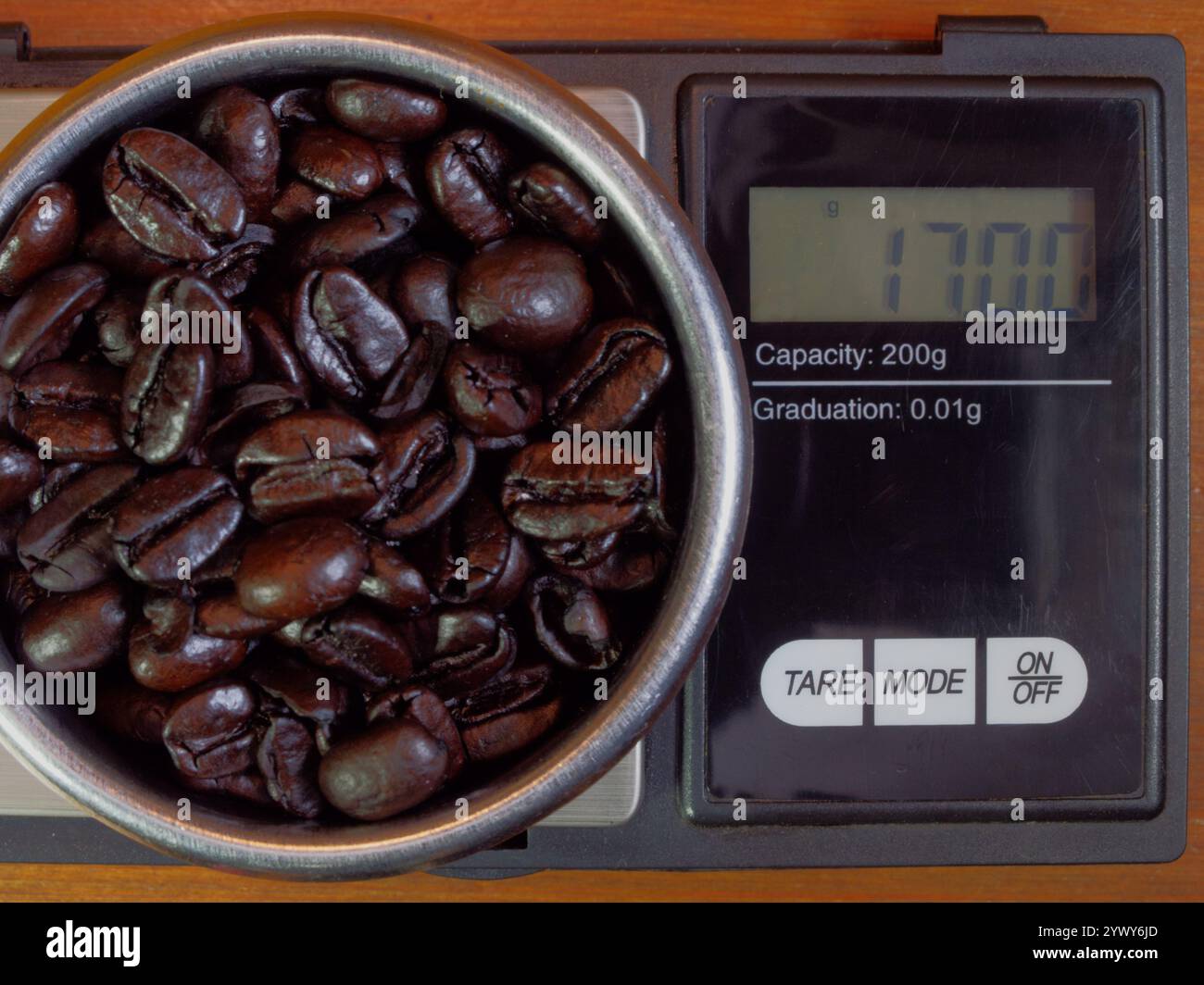 Großaufnahme von frischen braunen Kaffeebohnen, die auf einer modernen digitalen Waage gewogen werden. Stockfoto