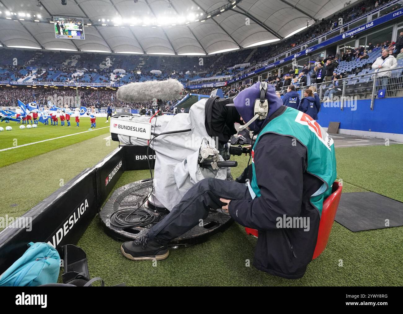 Hamburg, Deutschland. Dezember 2024. Fußball: Bundesliga 2, Spieltag 15, Hamburger SV - Darmstadt 98, im Volksparkstadion sitzt Ein Fernsehkameramann am Spielfeldrand. Hinweis: Marcus Brandt/dpa - WICHTIGER HINWEIS: Gemäß den Vorschriften der DFL Deutschen Fußball-Liga und des DFB Deutschen Fußball-Bundes ist es verboten, im Stadion und/oder des Spiels aufgenommene Fotografien in Form von sequenziellen Bildern und/oder videoähnlichen Fotoserien zu verwenden oder zu verwenden./dpa/Alamy Live News Stockfoto