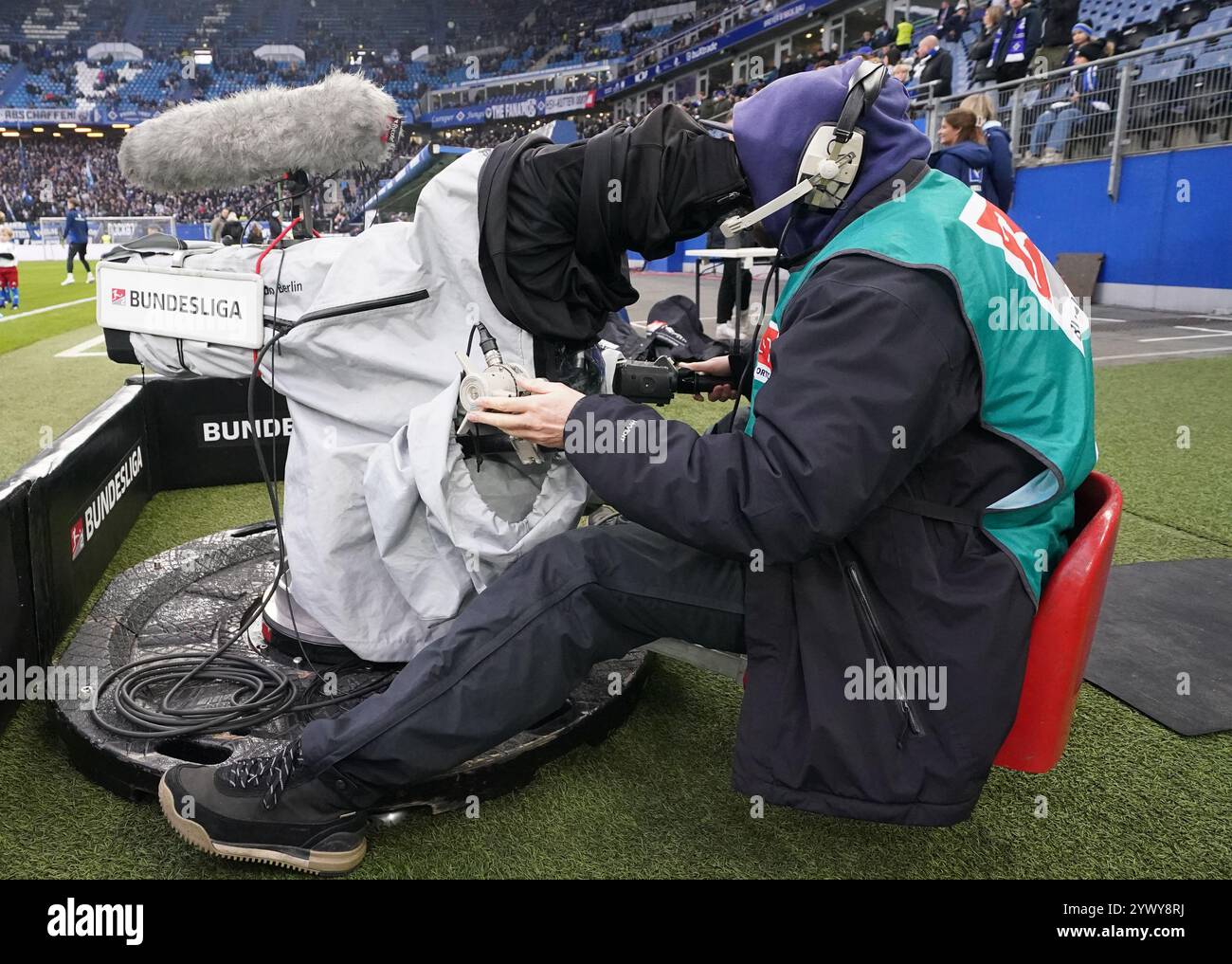Hamburg, Deutschland. Dezember 2024. Fußball: Bundesliga 2, Spieltag 15, Hamburger SV - Darmstadt 98, im Volksparkstadion sitzt Ein Fernsehkameramann am Spielfeldrand. Hinweis: Marcus Brandt/dpa - WICHTIGER HINWEIS: Gemäß den Vorschriften der DFL Deutschen Fußball-Liga und des DFB Deutschen Fußball-Bundes ist es verboten, im Stadion und/oder des Spiels aufgenommene Fotografien in Form von sequenziellen Bildern und/oder videoähnlichen Fotoserien zu verwenden oder zu verwenden./dpa/Alamy Live News Stockfoto