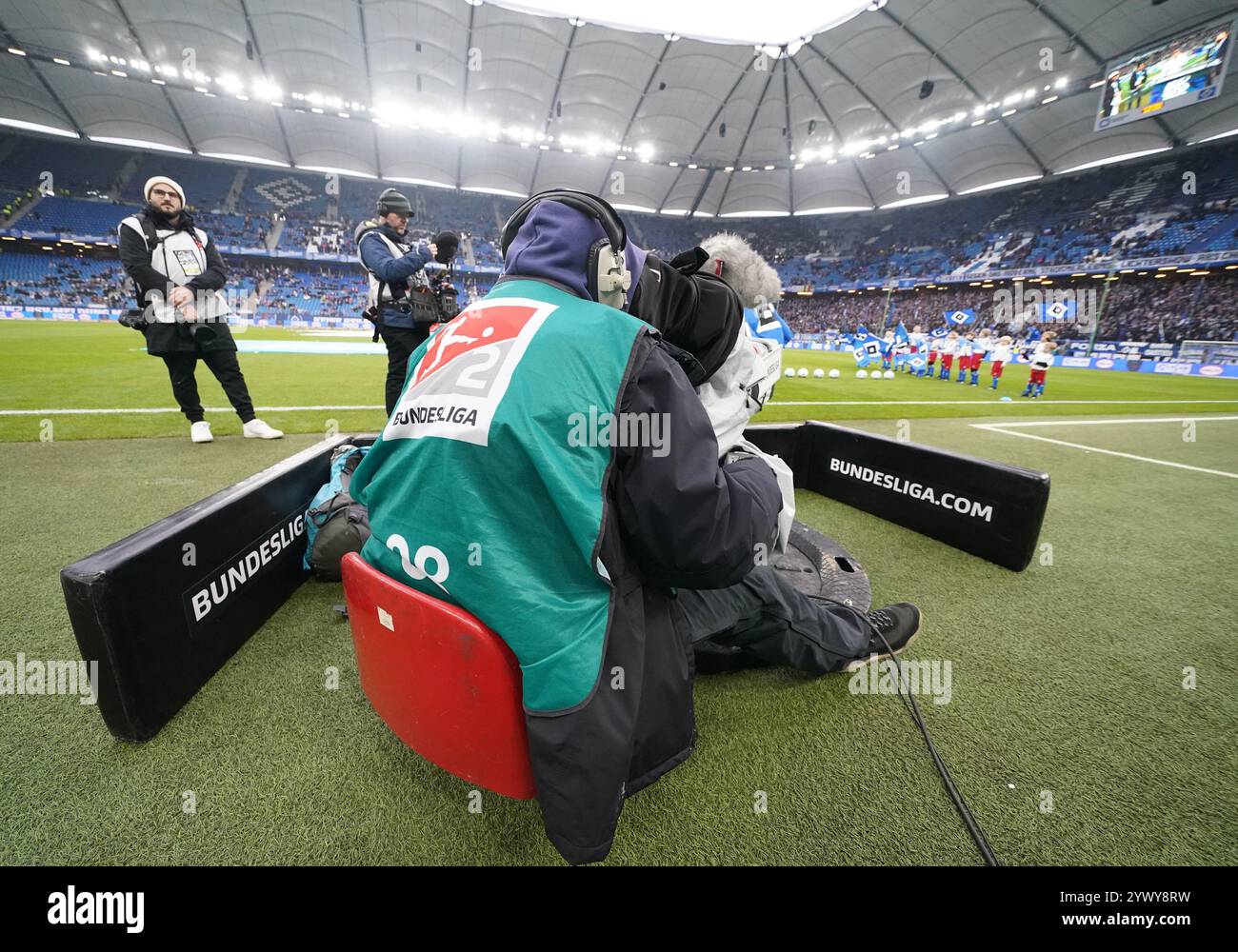 Hamburg, Deutschland. Dezember 2024. Fußball: Bundesliga 2, Spieltag 15, Hamburger SV - Darmstadt 98, im Volksparkstadion sitzt Ein Fernsehkameramann am Spielfeldrand. Hinweis: Marcus Brandt/dpa - WICHTIGER HINWEIS: Gemäß den Vorschriften der DFL Deutschen Fußball-Liga und des DFB Deutschen Fußball-Bundes ist es verboten, im Stadion und/oder des Spiels aufgenommene Fotografien in Form von sequenziellen Bildern und/oder videoähnlichen Fotoserien zu verwenden oder zu verwenden./dpa/Alamy Live News Stockfoto