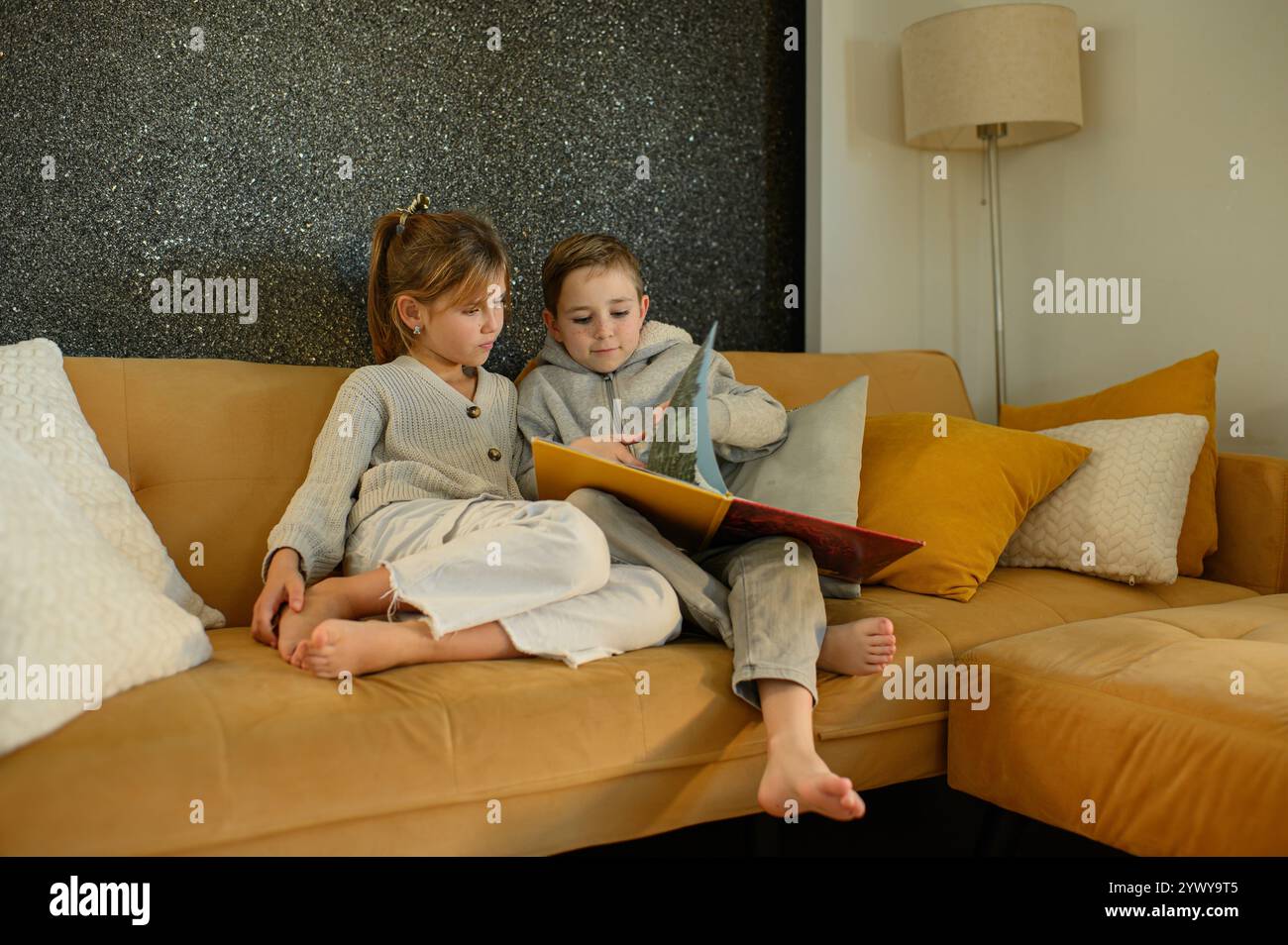 Junge und Mädchen lesen zu Hause Bücher auf dem Sofa Stockfoto