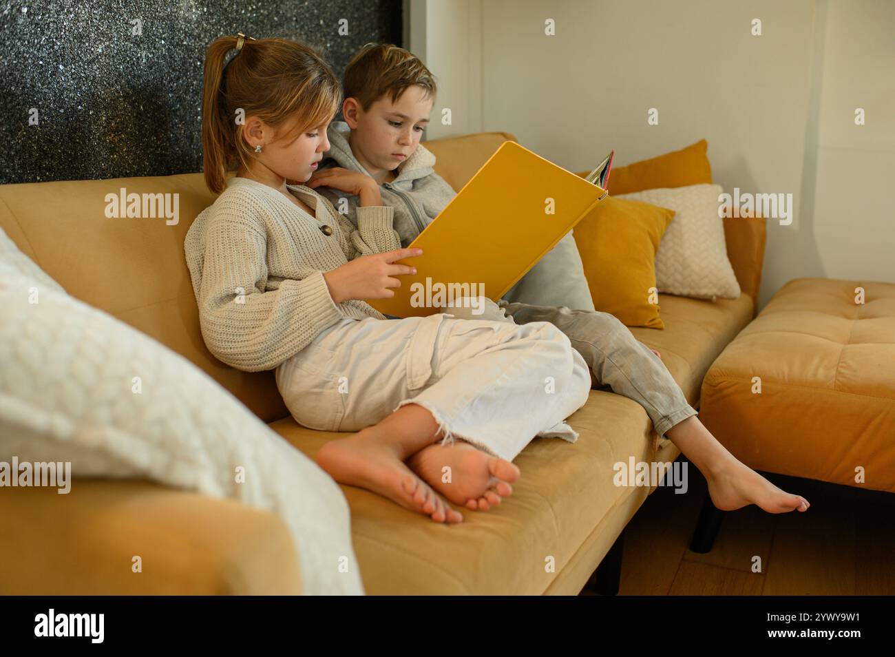 Junge und Mädchen lesen zu Hause Bücher auf dem Sofa Stockfoto