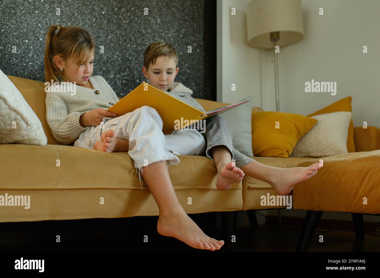 Junge und Mädchen lesen zu Hause Bücher auf dem Sofa Stockfoto