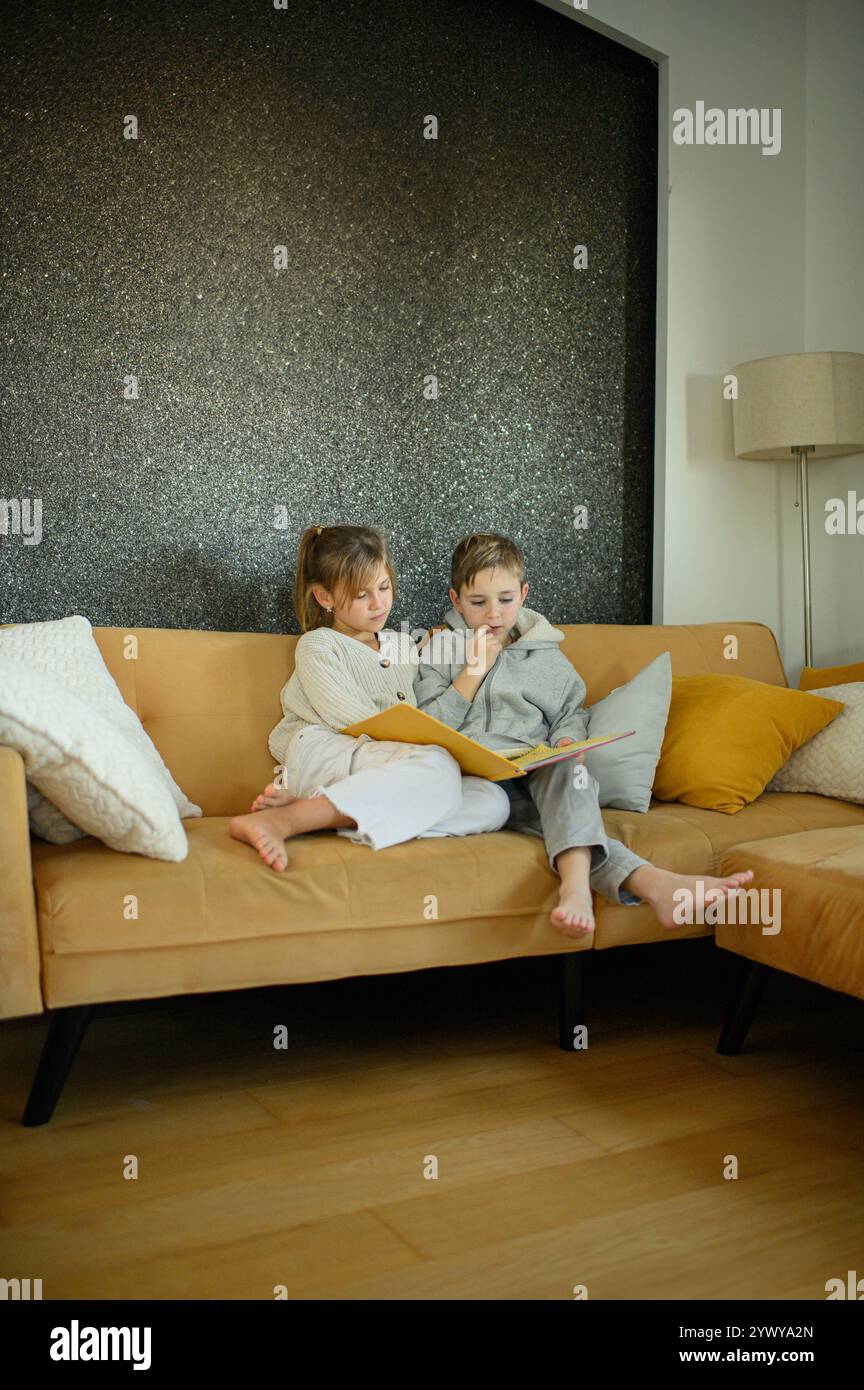 Junge und Mädchen lesen zu Hause Bücher auf dem Sofa Stockfoto