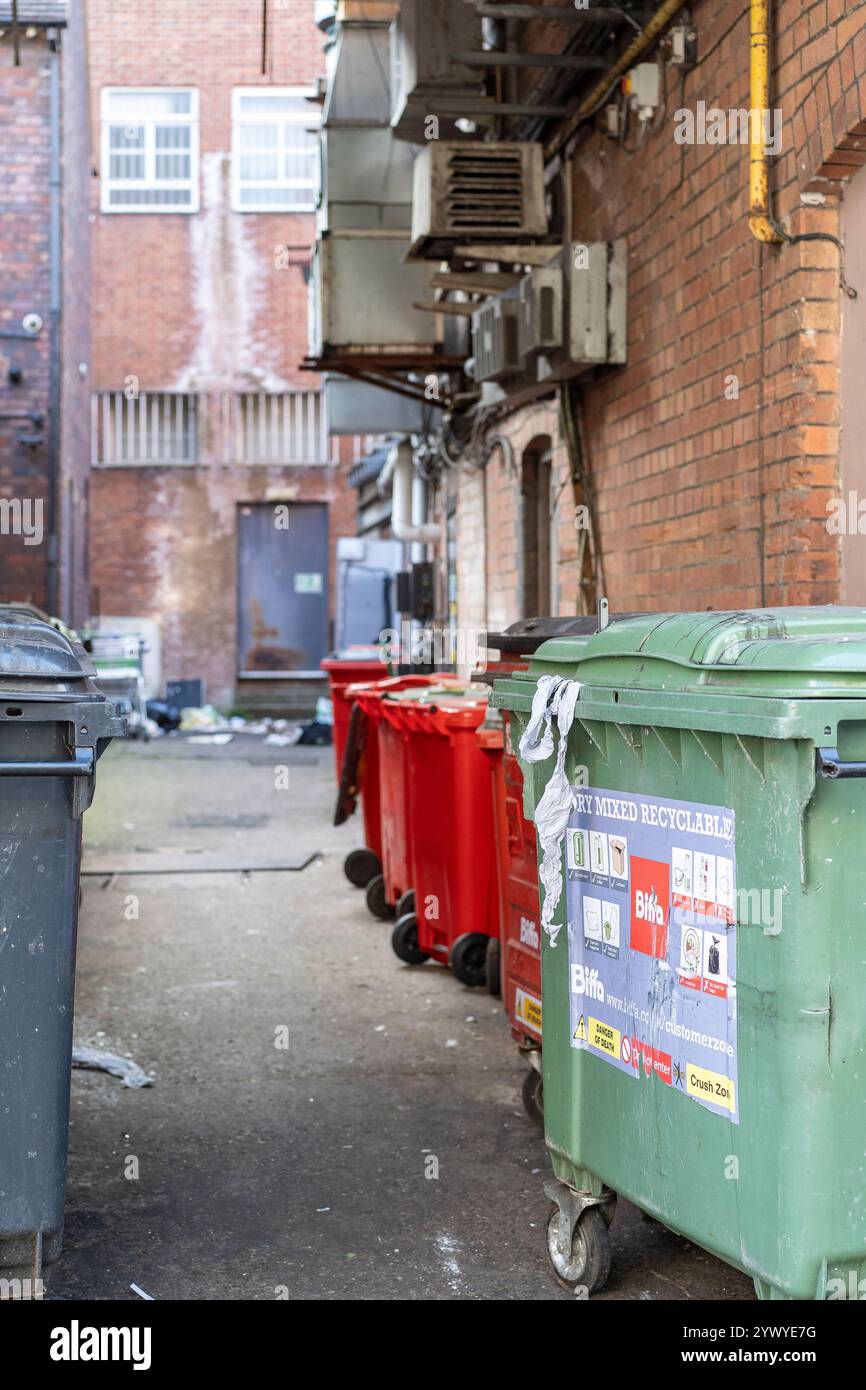 Große Mülltonnen für gewerbliche Zwecke in der Hintergasse hinter Gebäuden von Einzelhandelsgeschäften/Geschäftsräumen in einem britischen Stadtzentrum. Stockfoto