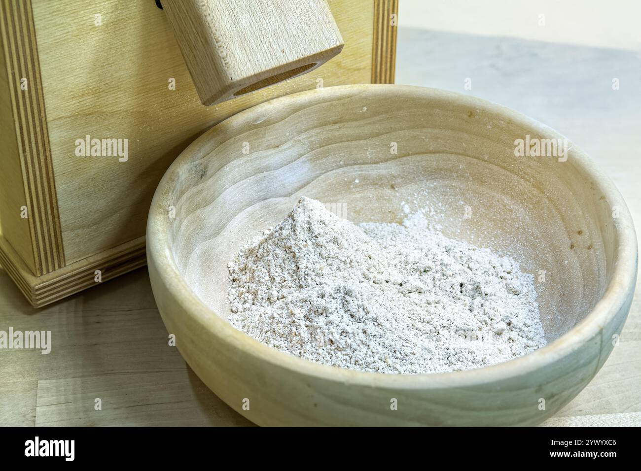 Manuelle Getreidemühle aus Holz und Holzschale mit biologischem Grobmehl. Stockfoto