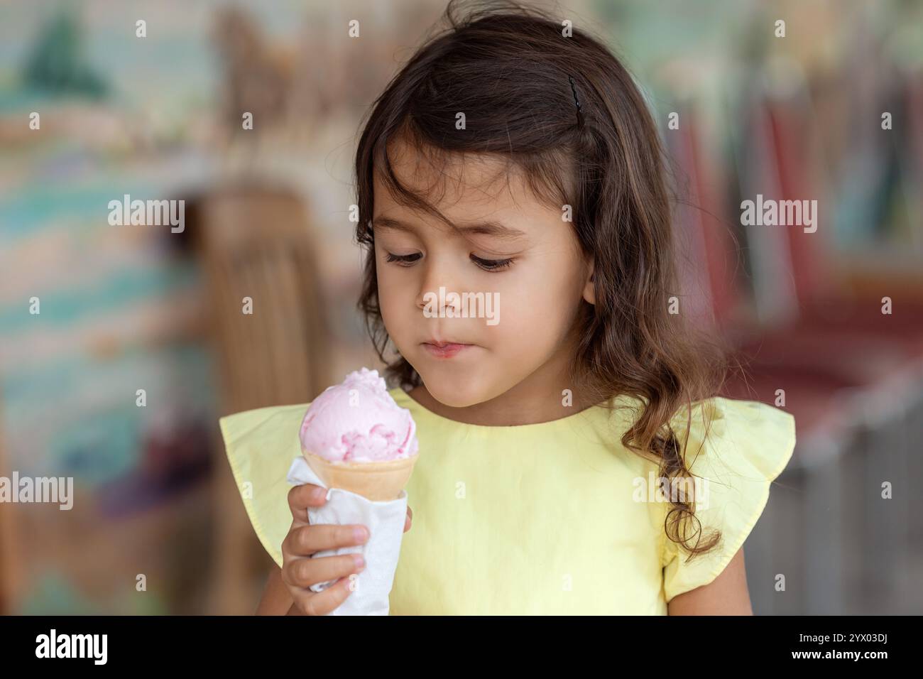 Kleines Mädchen im Sommerkleid isst Eis an einem heißen Tag im Café, Kindheitserinnerungen und Sommerferienkonzept - Bild Stockfoto