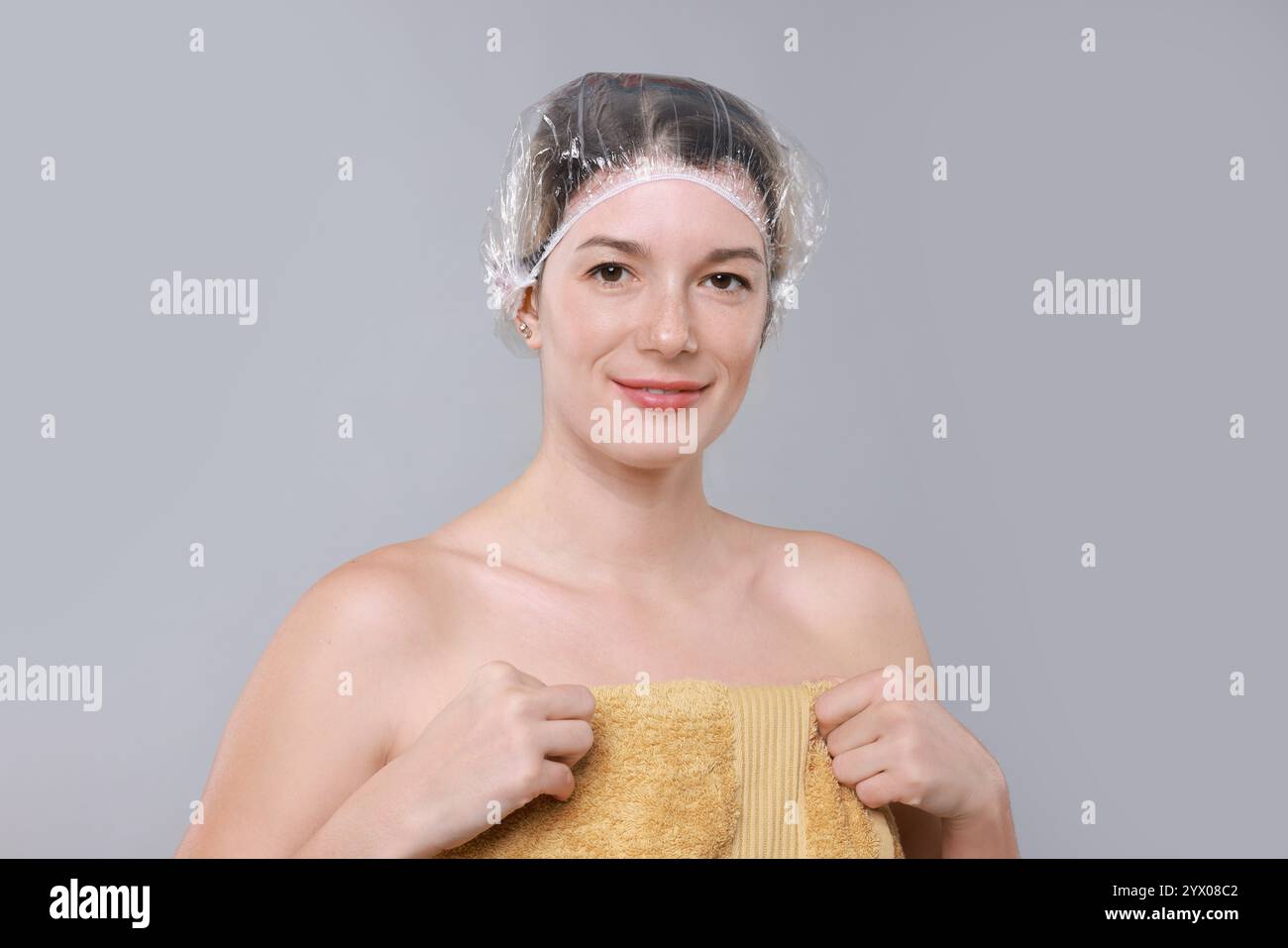 Frau in Duschhaube auf grauem Hintergrund Stockfoto