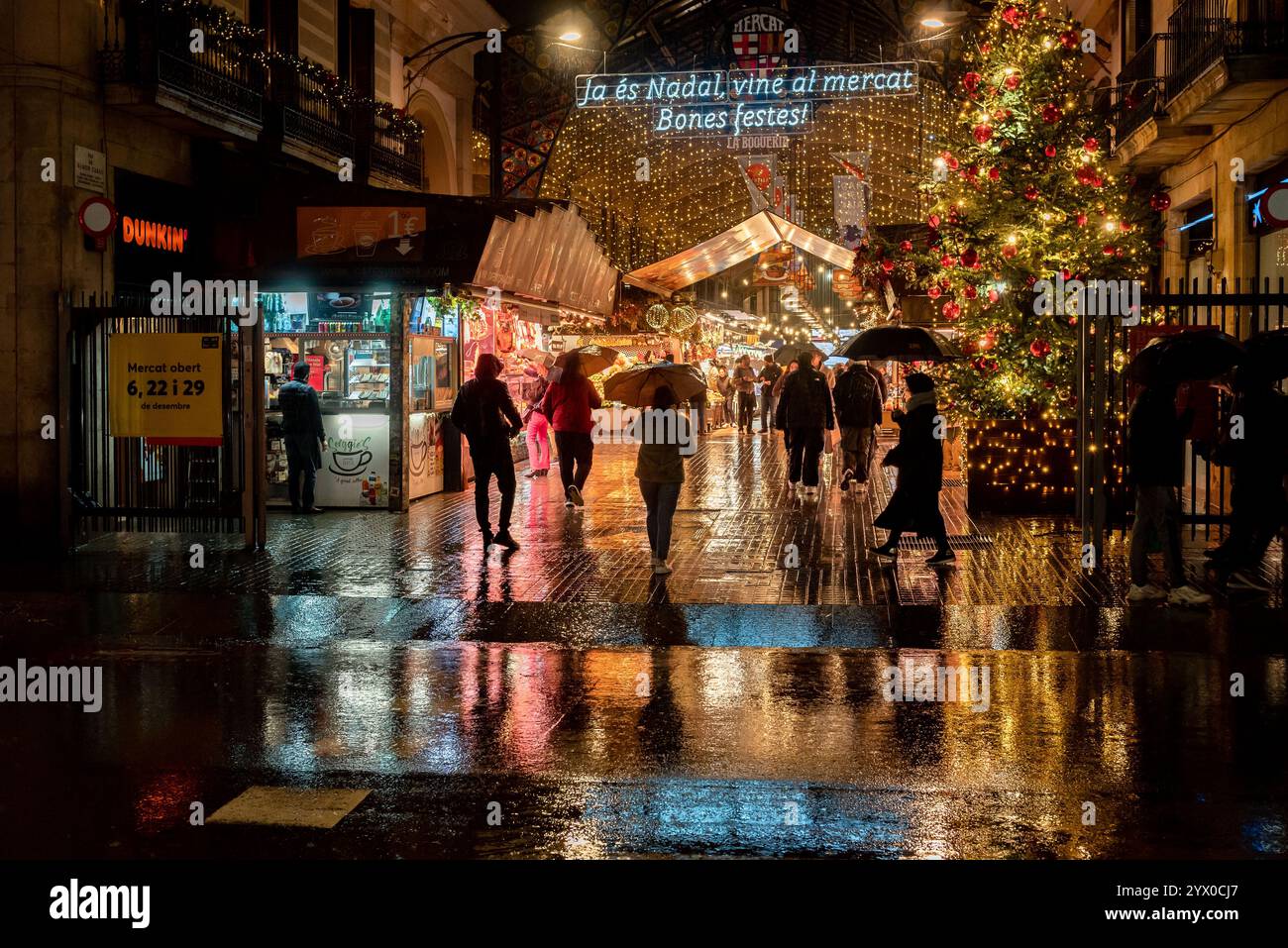 12. Dezember 2024, Barcelona, Spanien: Die Weihnachtslichter am Eingang des Markts La Boqueria spiegeln sich während eines regnerischen Abends in der katalanischen Hauptstadt auf dem Boden der Rambla. Quelle: Jordi Boixareu/Alamy Life News Stockfoto