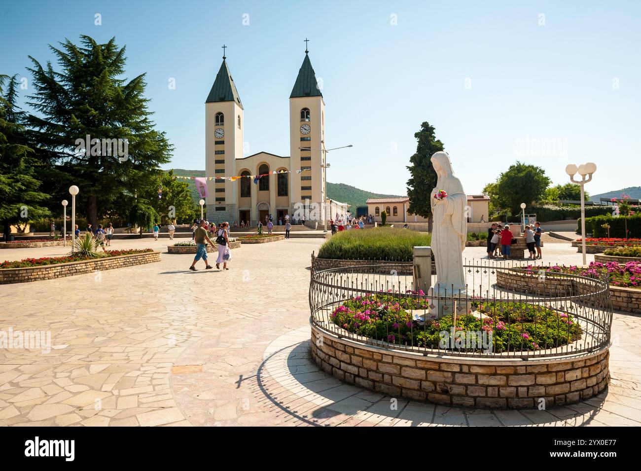 Wallfahrtsort Medjugorje in Bosnien und Herzegowina. Im Vordergrund steht die Statue der Vigin Maria und im Hintergrund die Pfarrkirche. Stockfoto